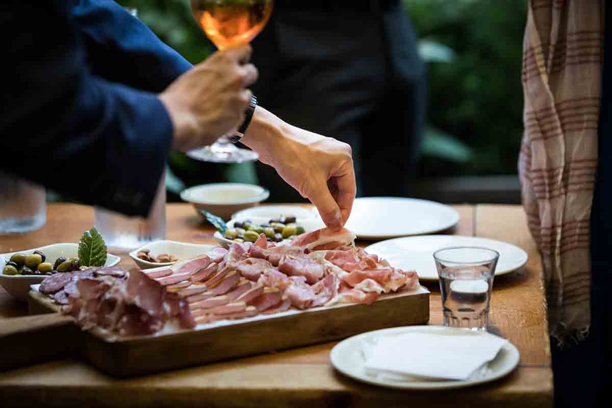 Hand picking up meat from a platter during wedding Il Buco Alimentari and Vineria wedding reception