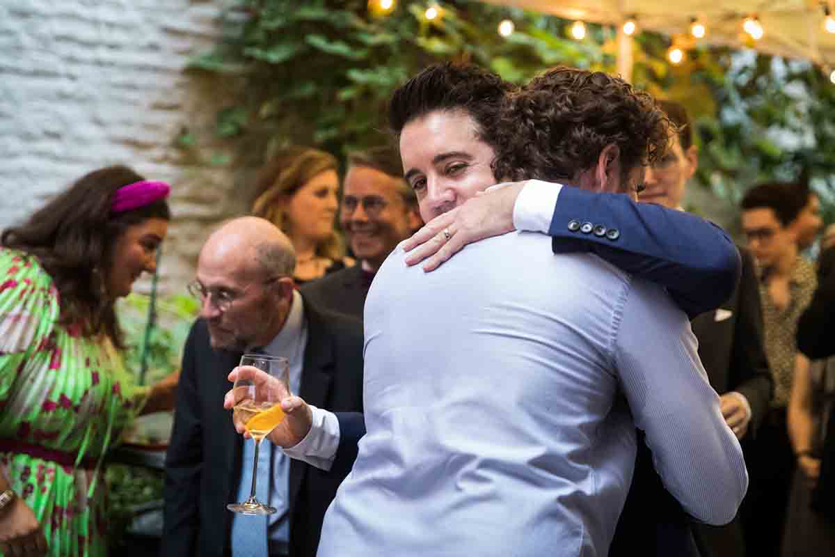 Groom hugging male guest during wedding Il Buco Alimentari and Vineria wedding reception