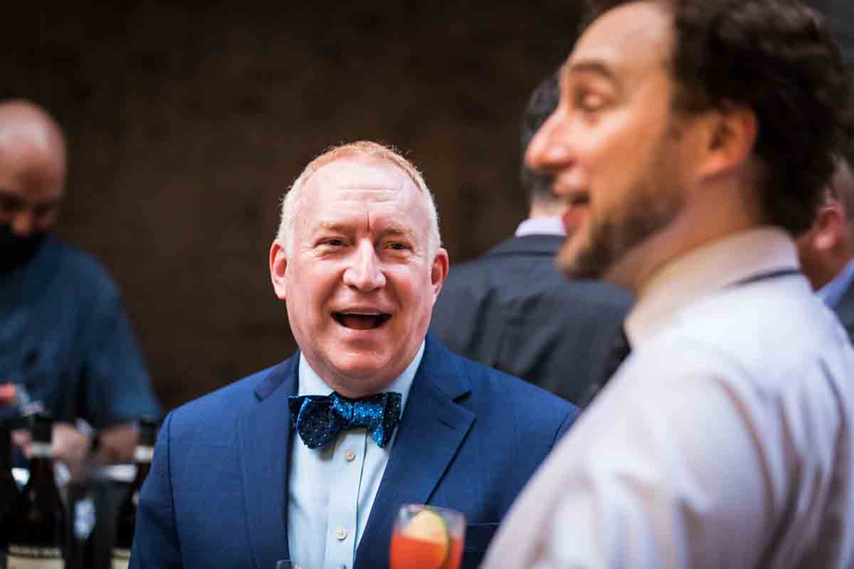 Older gentleman wearing blue bow tie listening to male guest