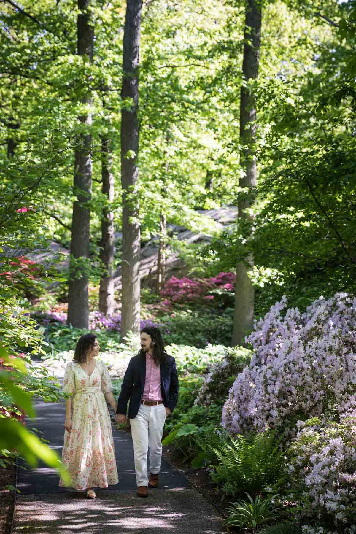 Couple walking down pathway lined with blooming azaleas in the New York Botanical Garden