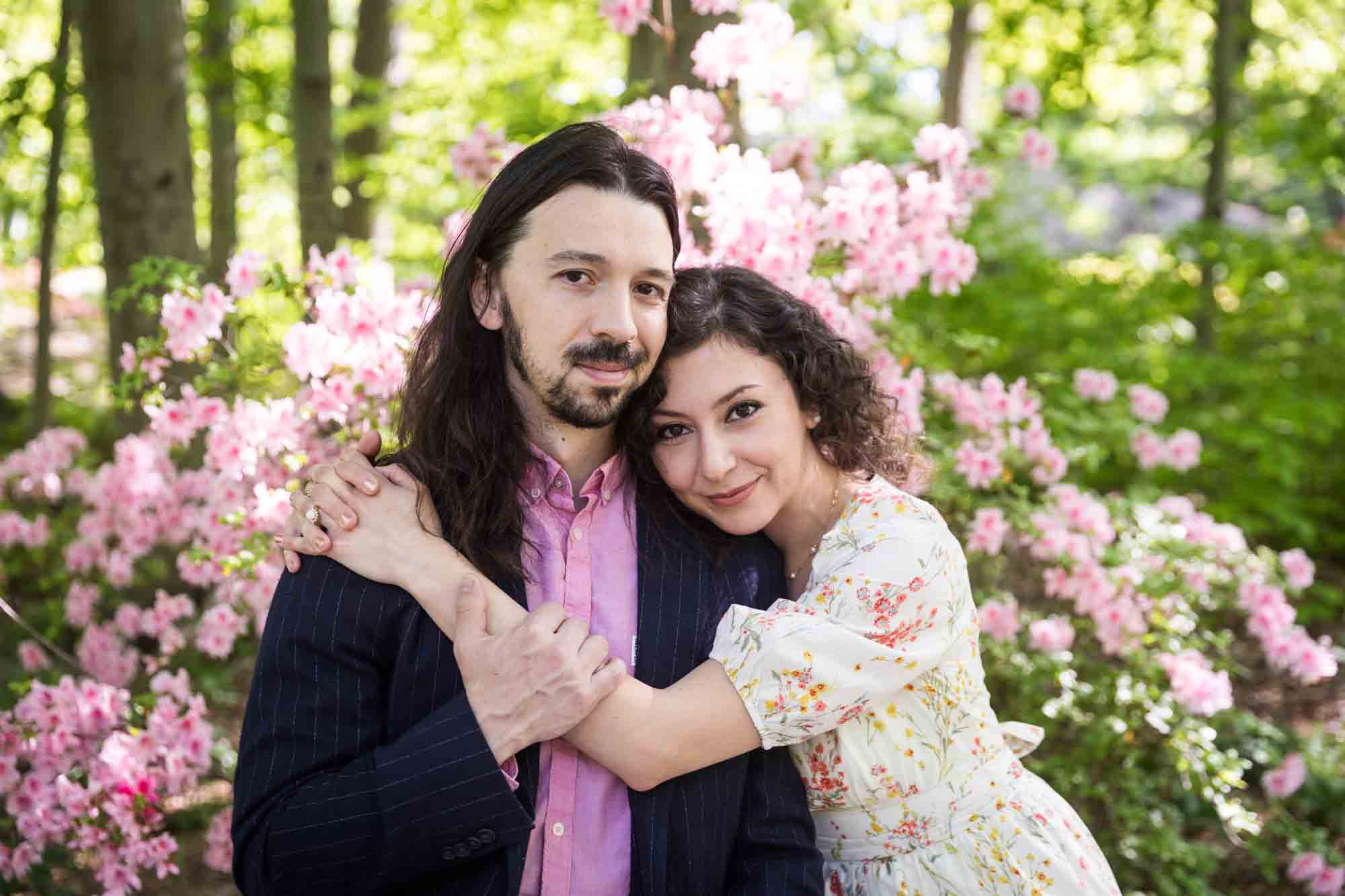 New York Botanical Garden engagement photos of couple hugging in front of pink azaleas
