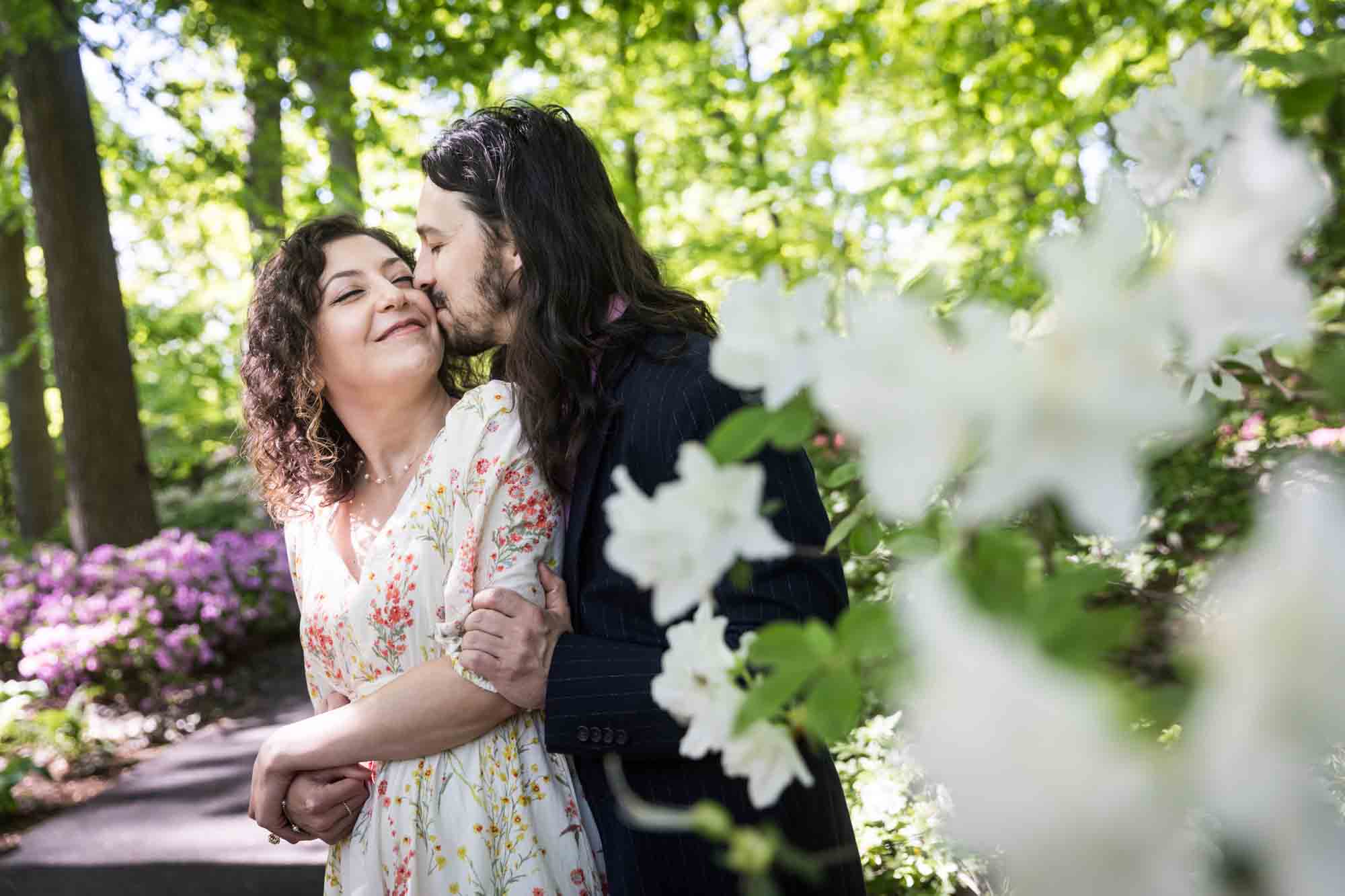New York Botanical Garden engagement photos of couple kissing behind white azaleas