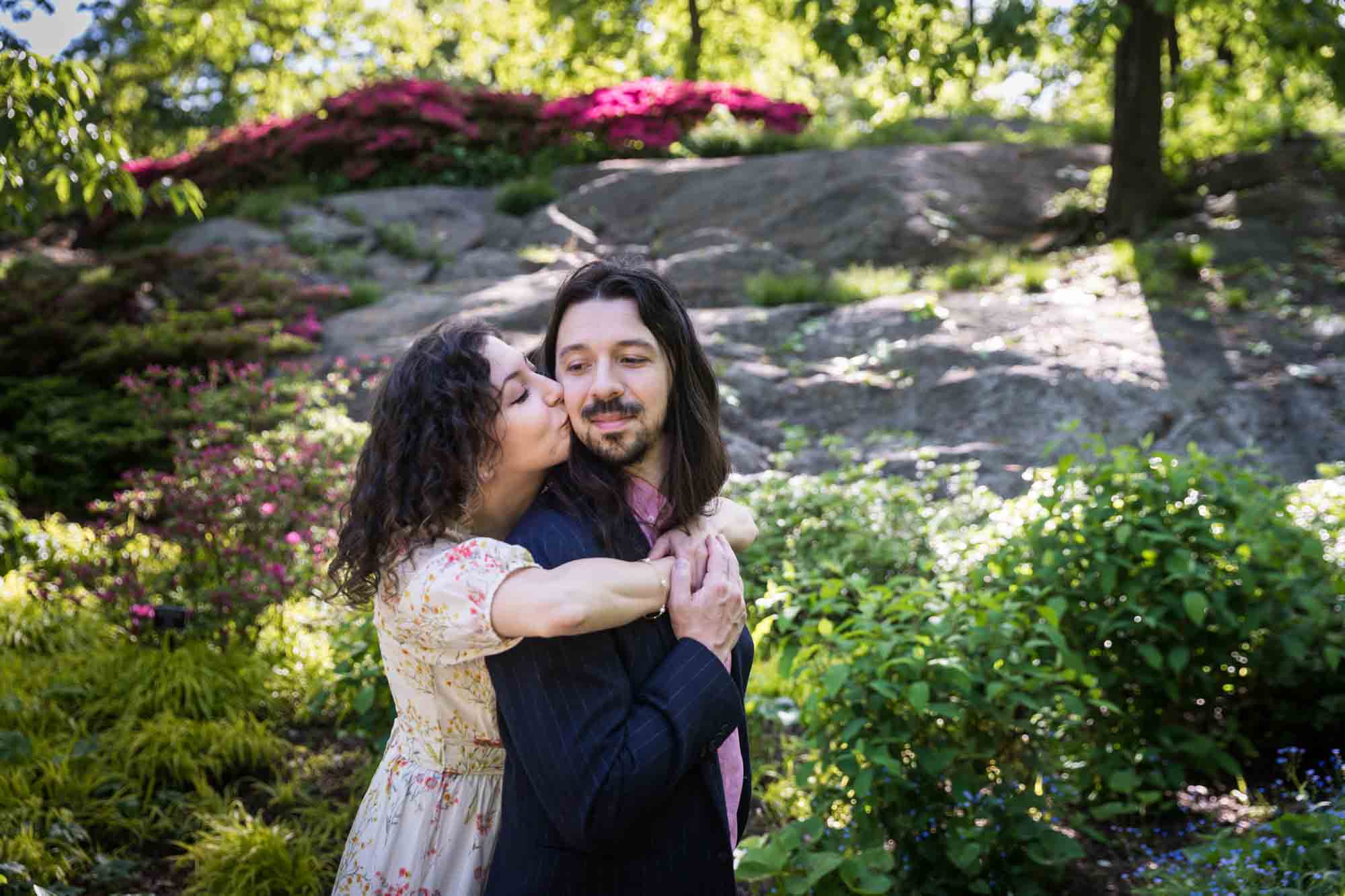 New York Botanical Garden engagement photos of woman kissing man on the cheek in front of garden
