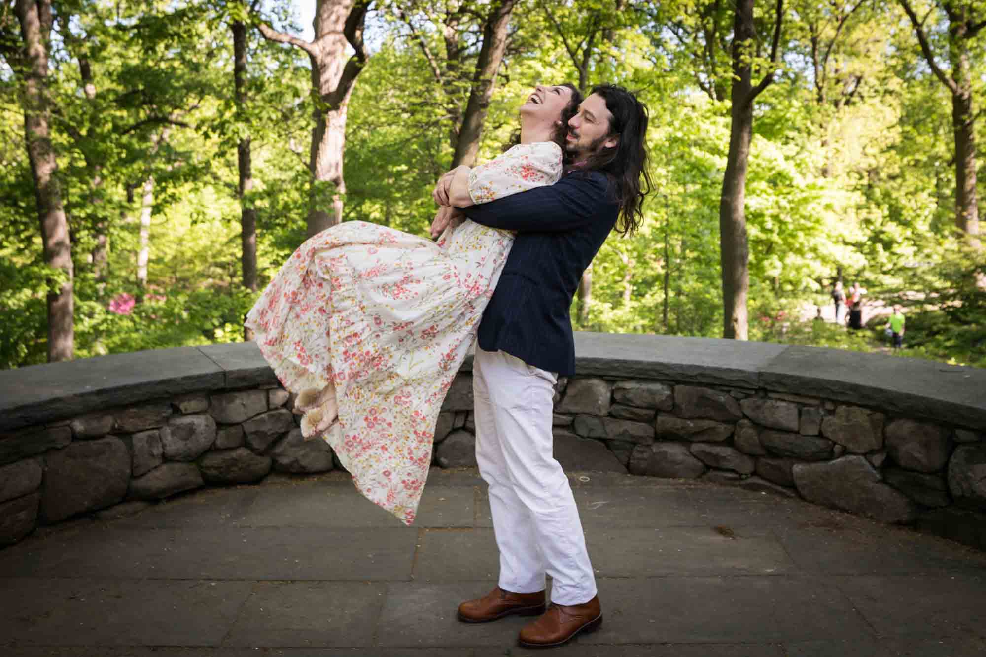 Man picking up woman in the New York Botanical Garden during an engagement photo shoot