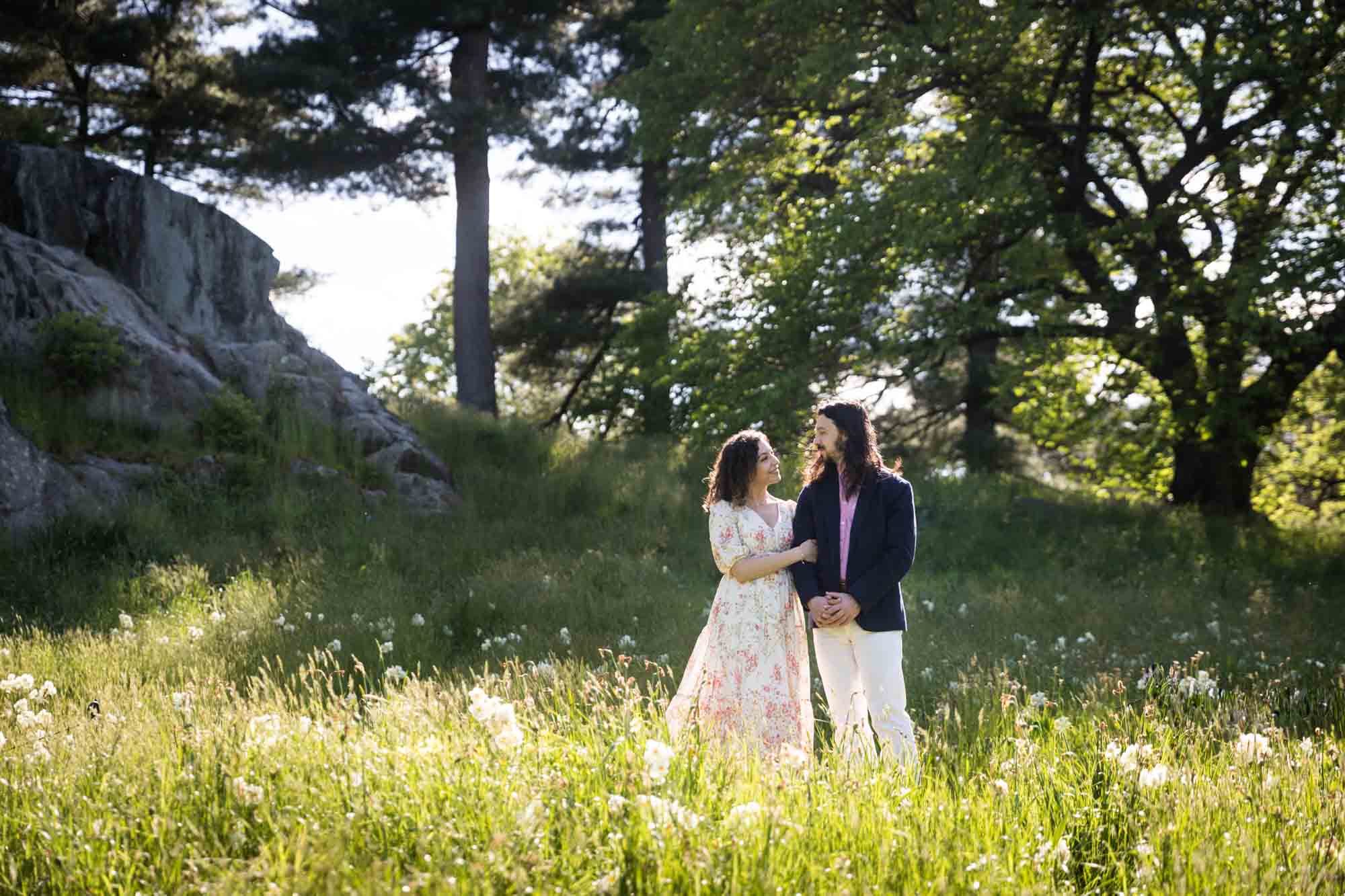 Couple standing in a meadow in the New York Botanical Garden during engagement portrait session