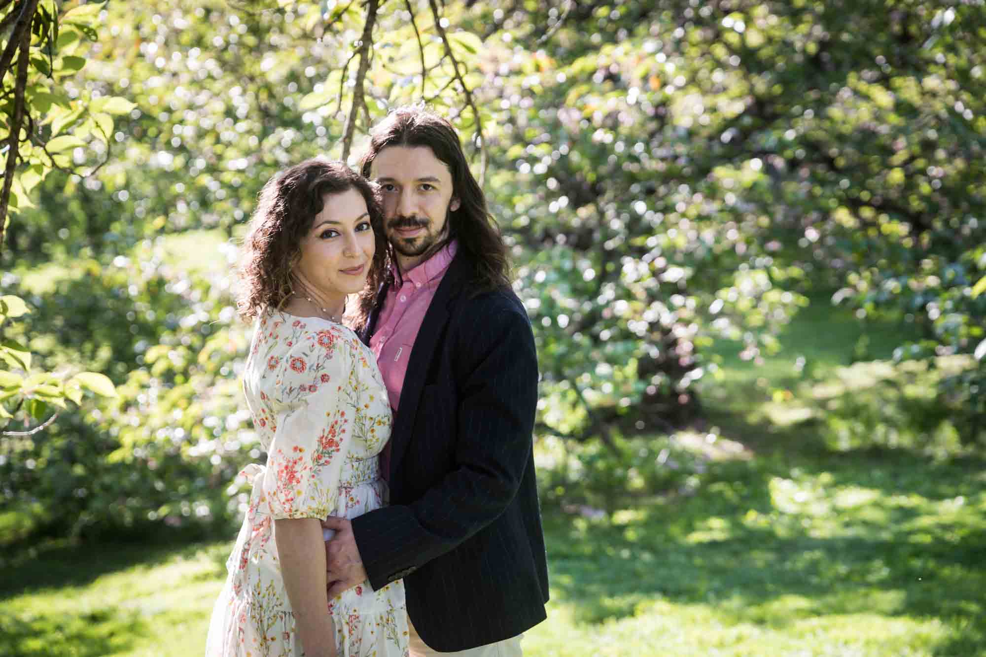 Couple hugging under cherry trees in New York Botanical Garden