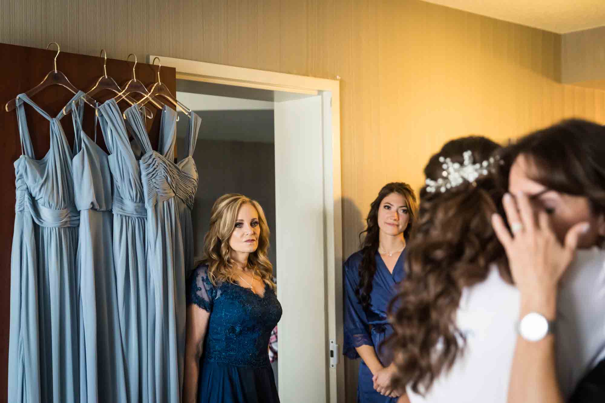 Mother watching bride hug aunt