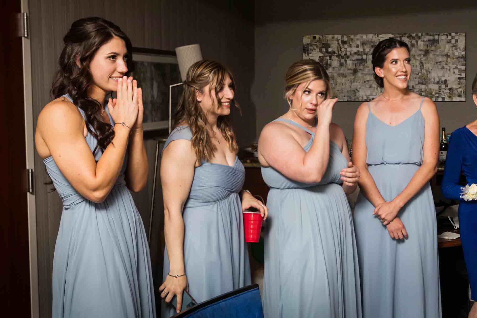 Bridesmaids wiping away tears and wearing grey dresses