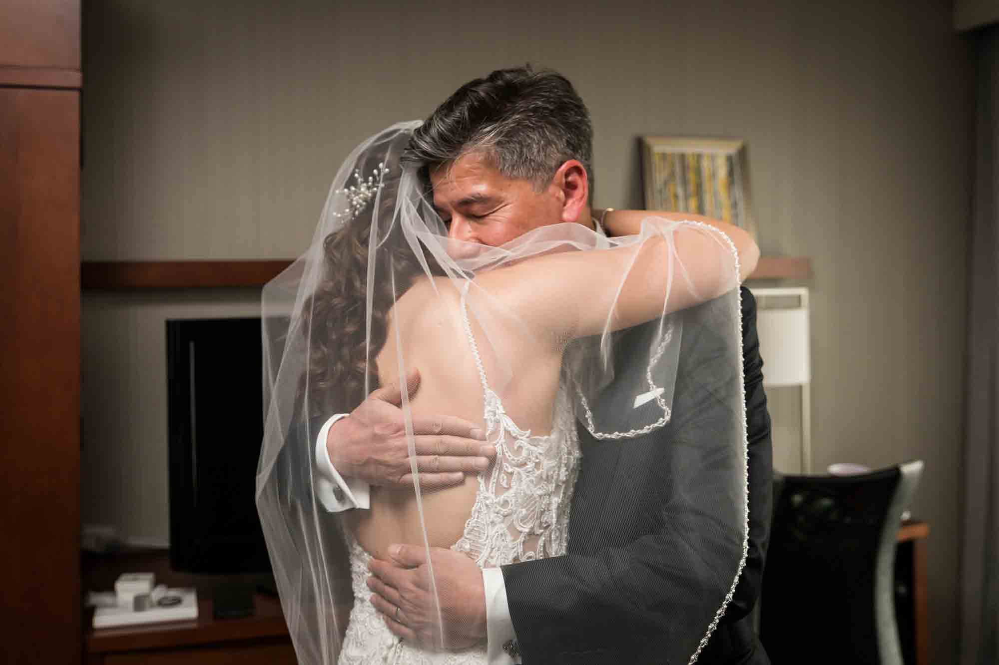 Bride wearing veil hugging father