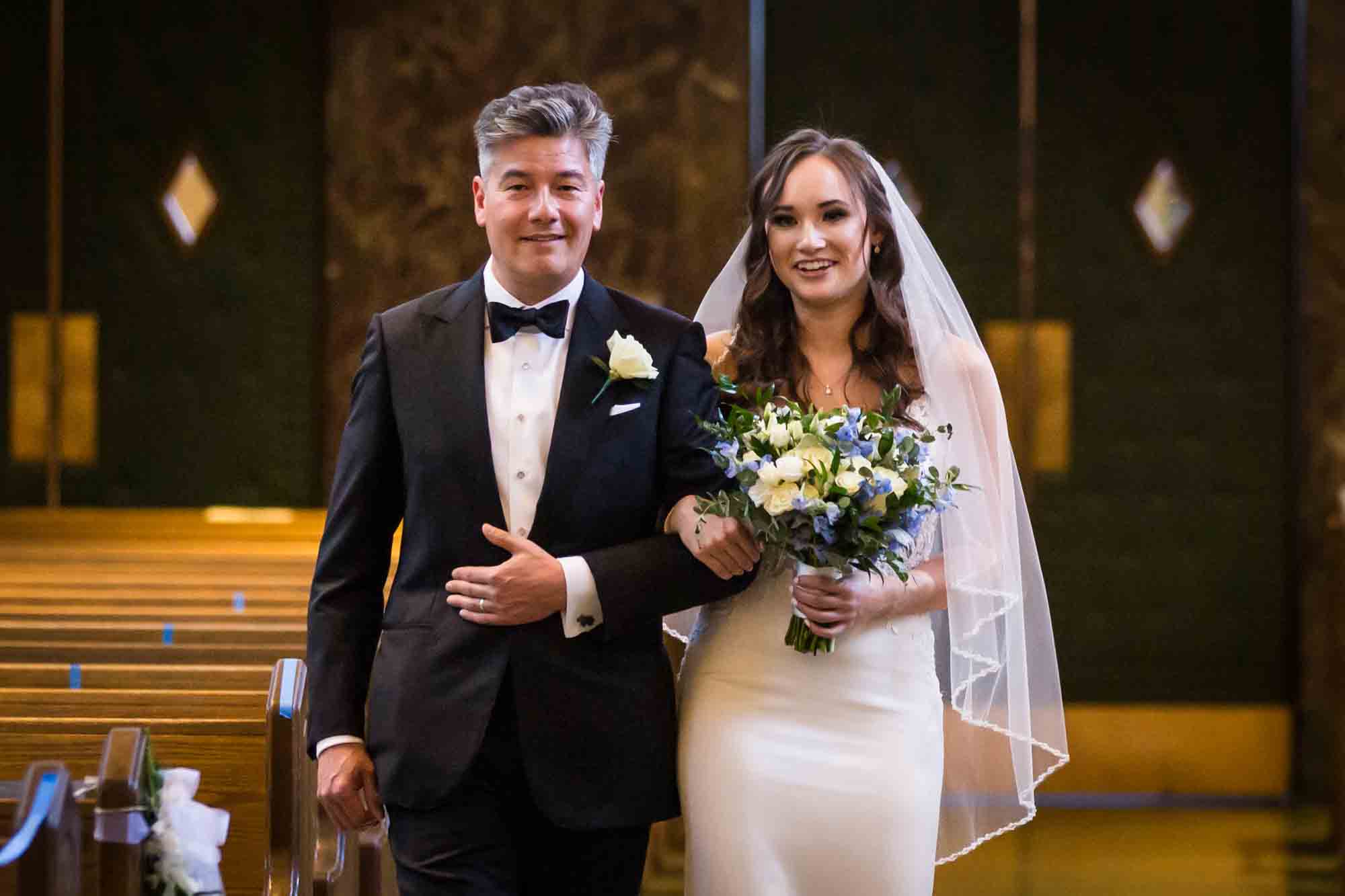 Bride and father walking down church aisle