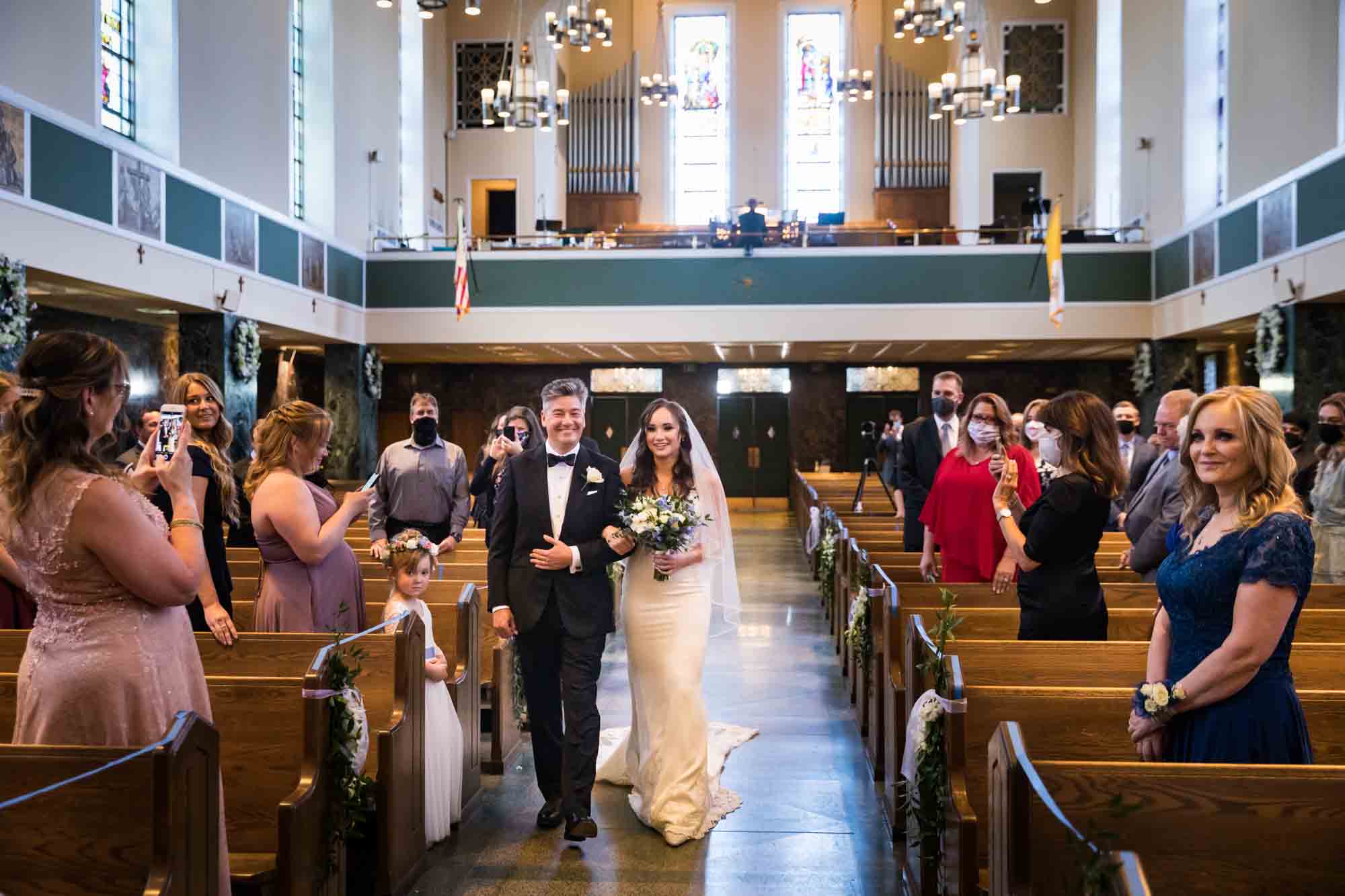 Wide shot of bride and father walking down aisle