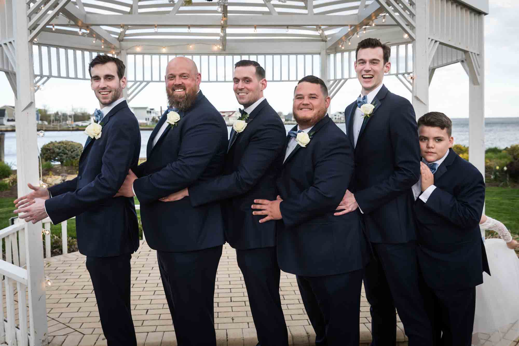 Riviera Waterfront Mansion wedding photos of groomsmen holding each other