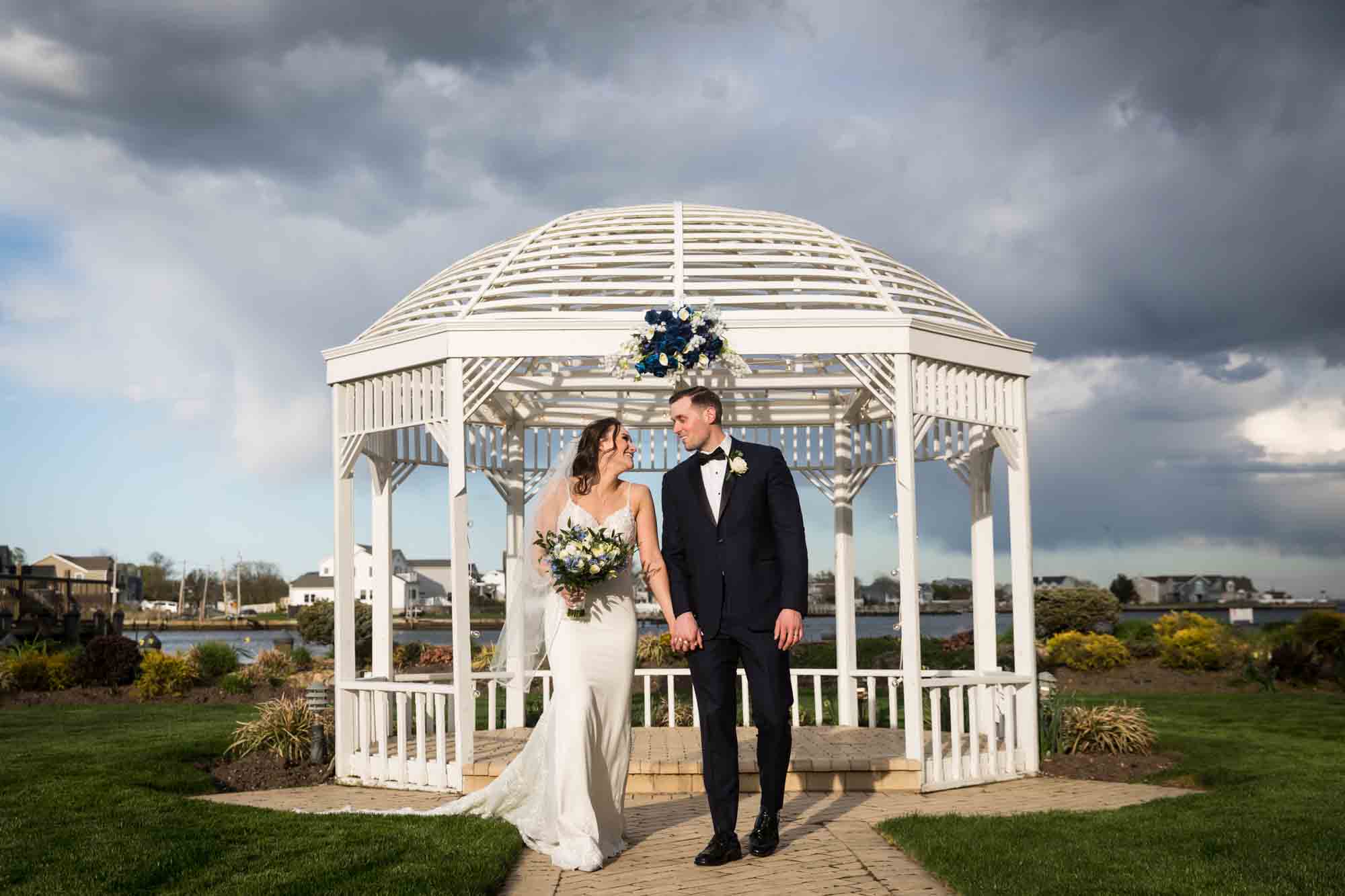 Riviera Waterfront Mansion wedding photos of bride and groom in front of white gazebo