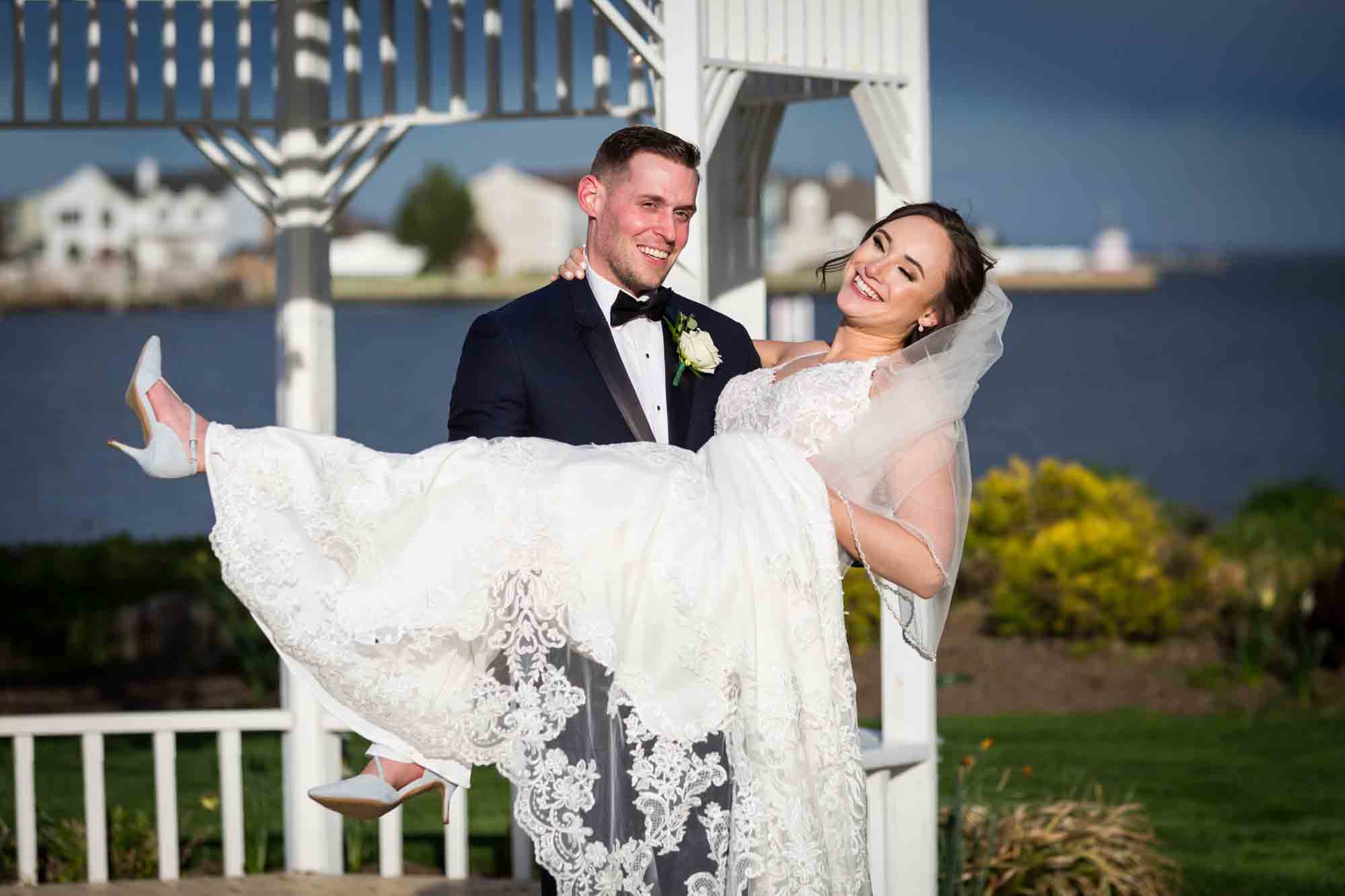 Groom holding bride in front of white gazebo