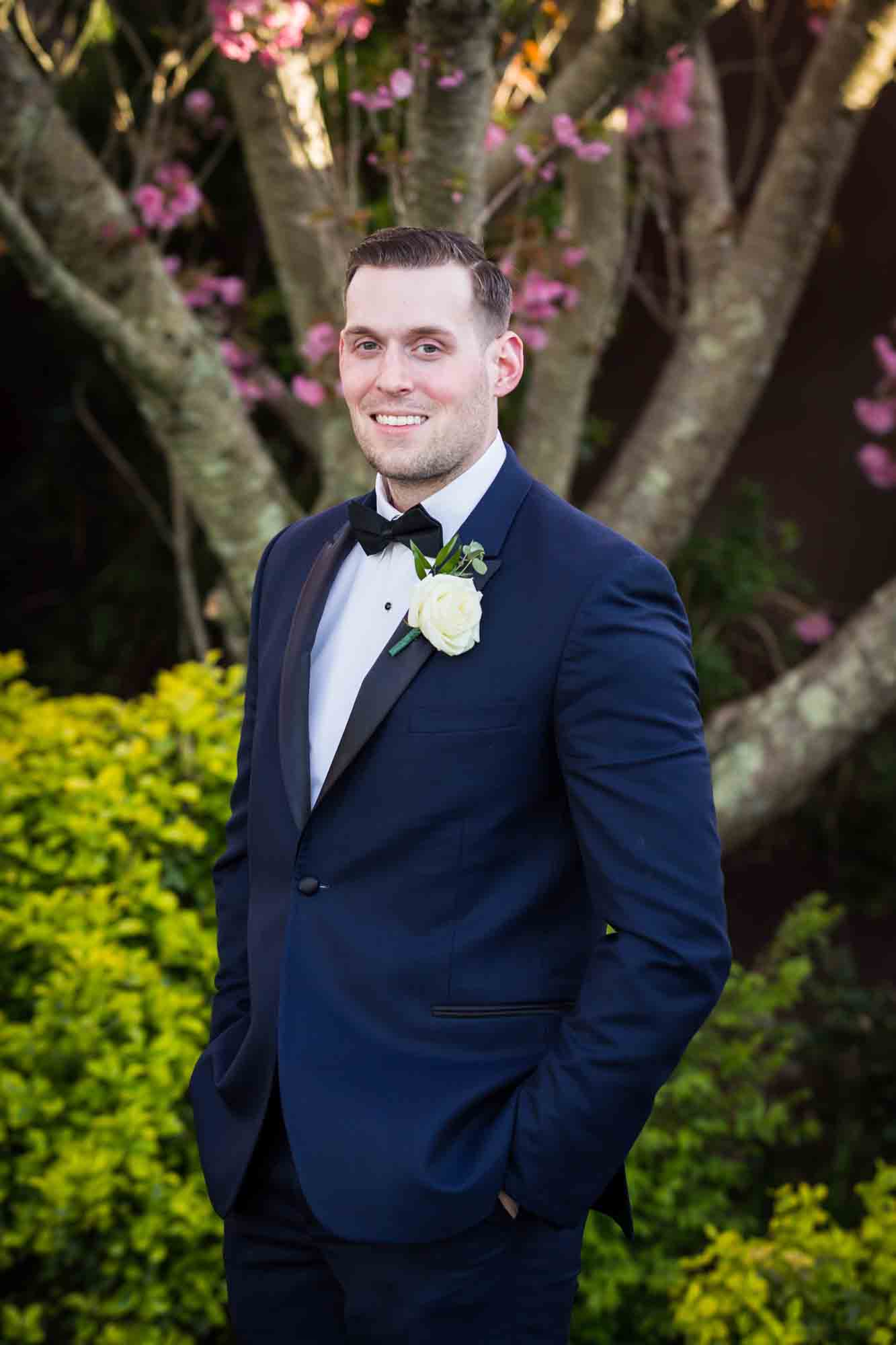 Riviera Waterfront Mansion wedding photos of groom standing in front of tree