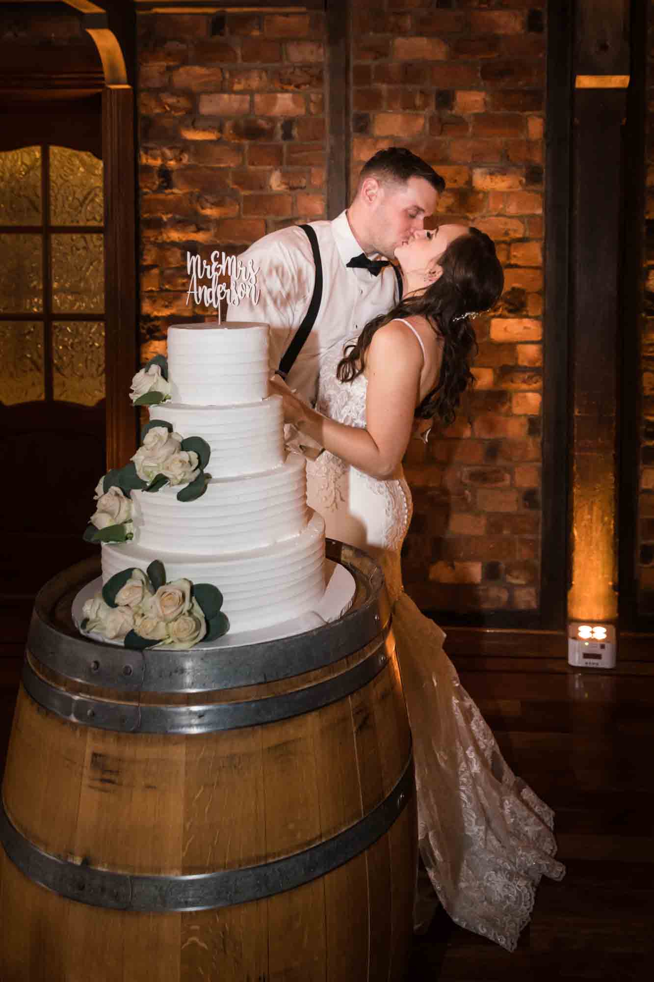 Bride and groom kissing in front of wedding cake