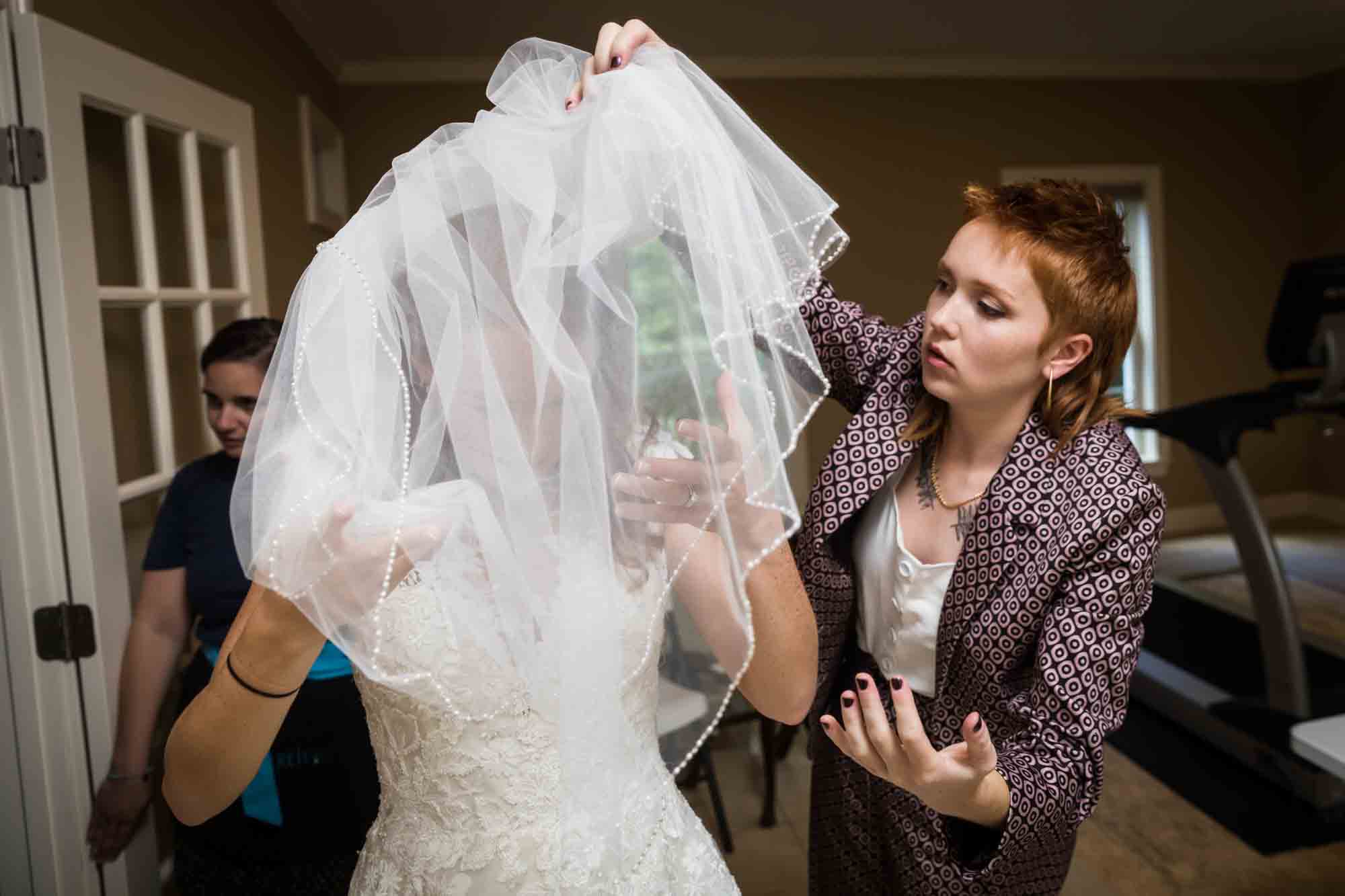Woman helping bride with veil for an article on backyard wedding tips