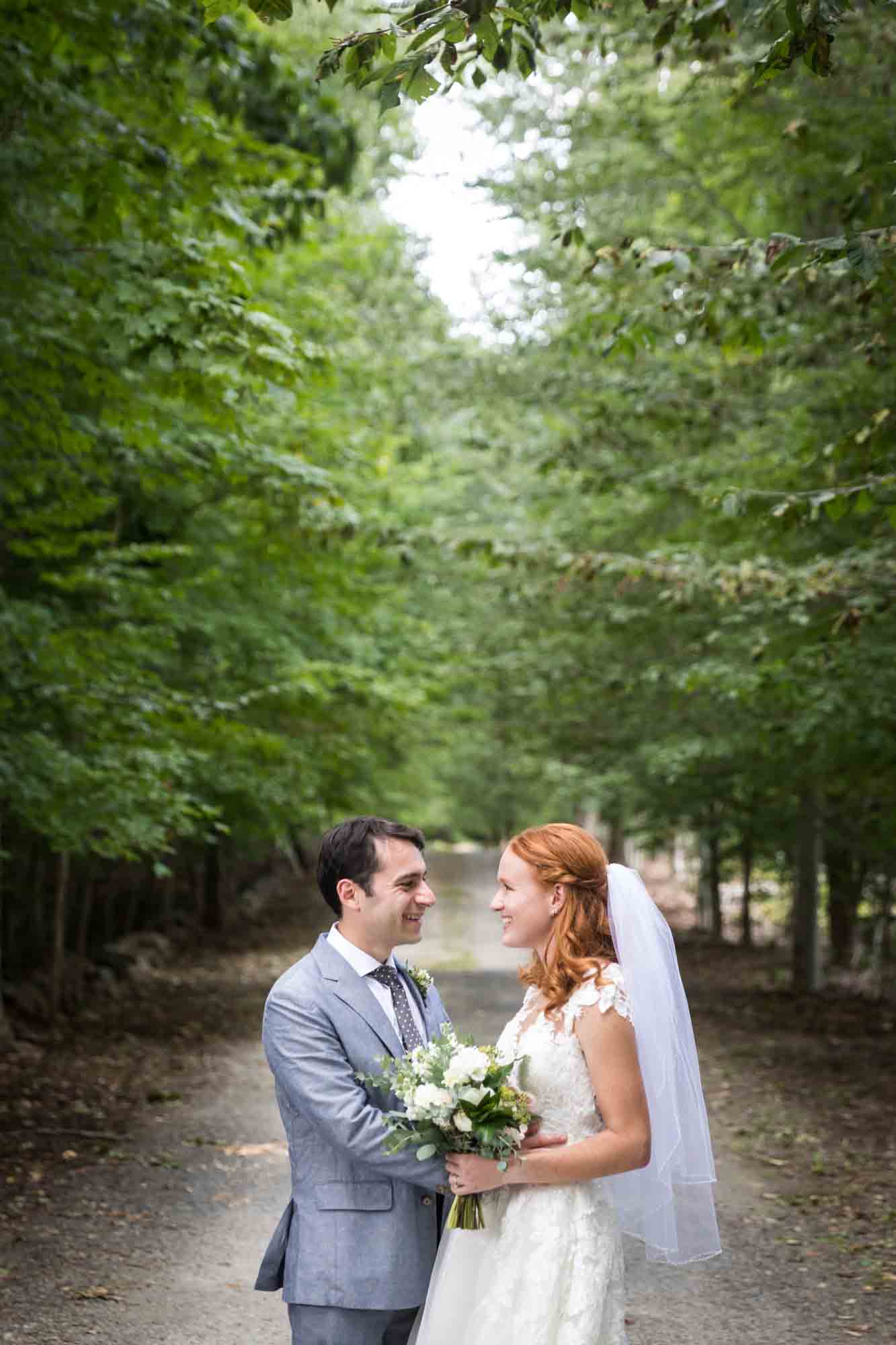 Bride and groom looking at each other with trees overhead for an article on backyard wedding tips