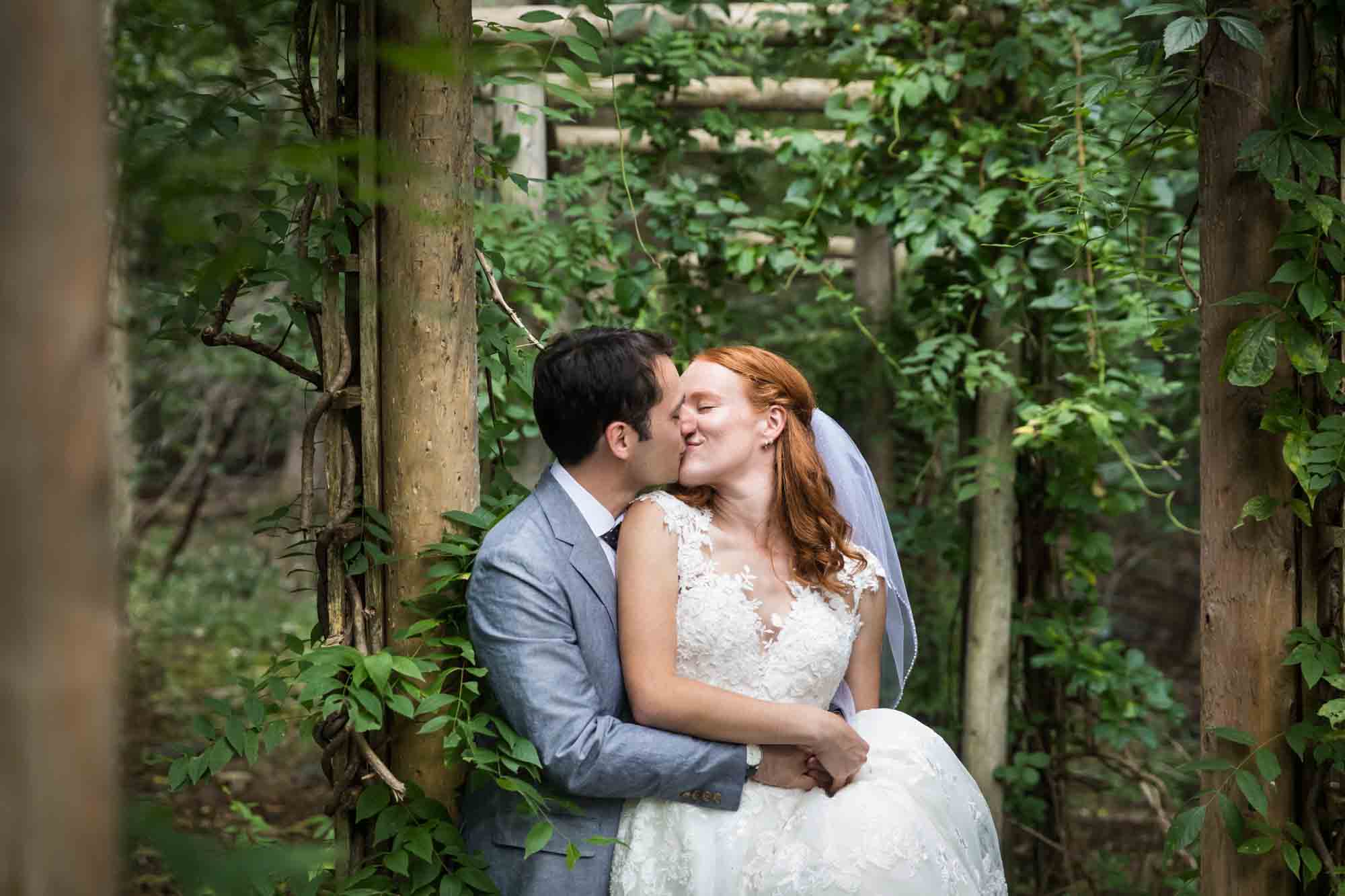 Bride and groom kissing in forest for an article on backyard wedding tips