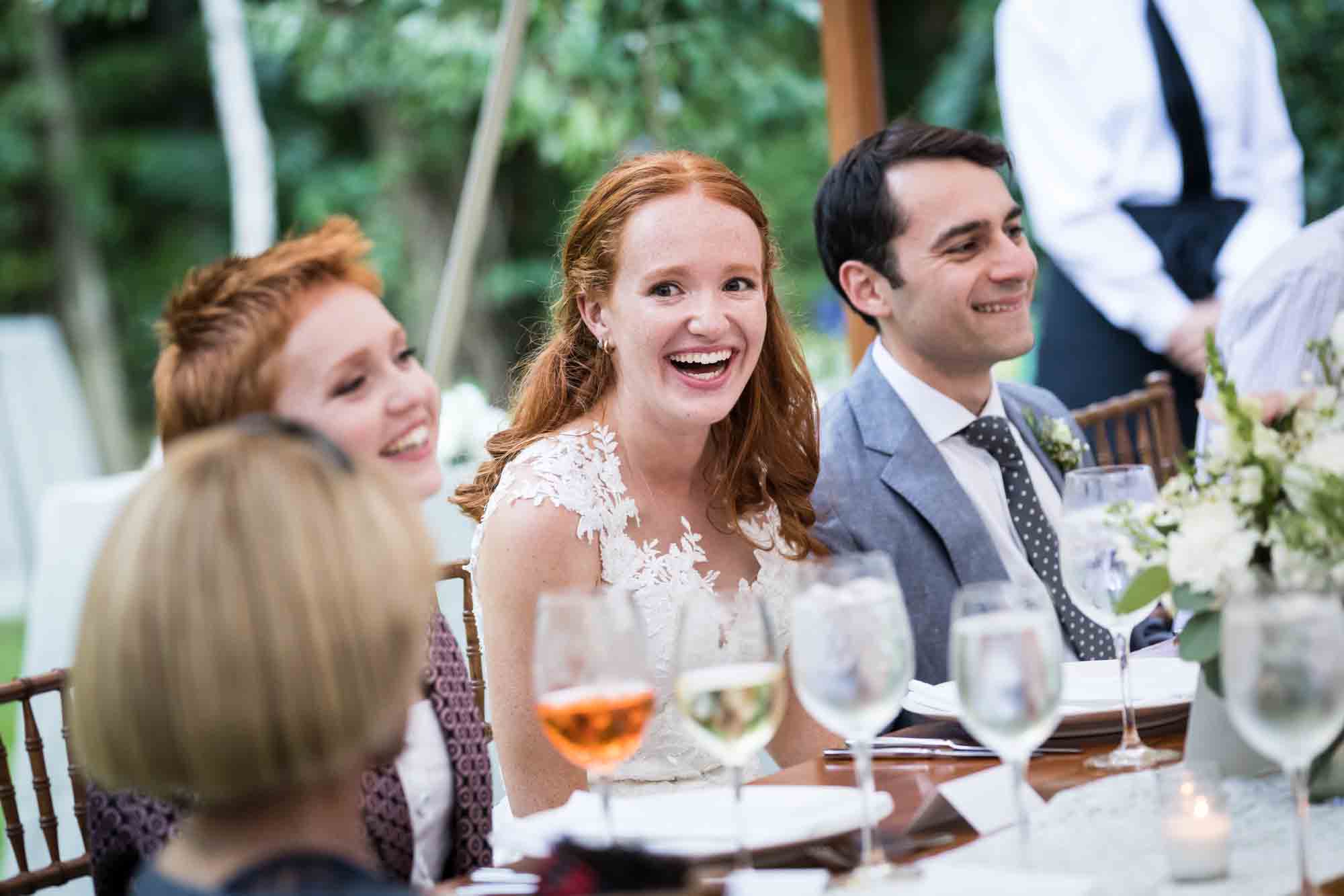 Bride and guests laughing at table for an article on backyard wedding tips