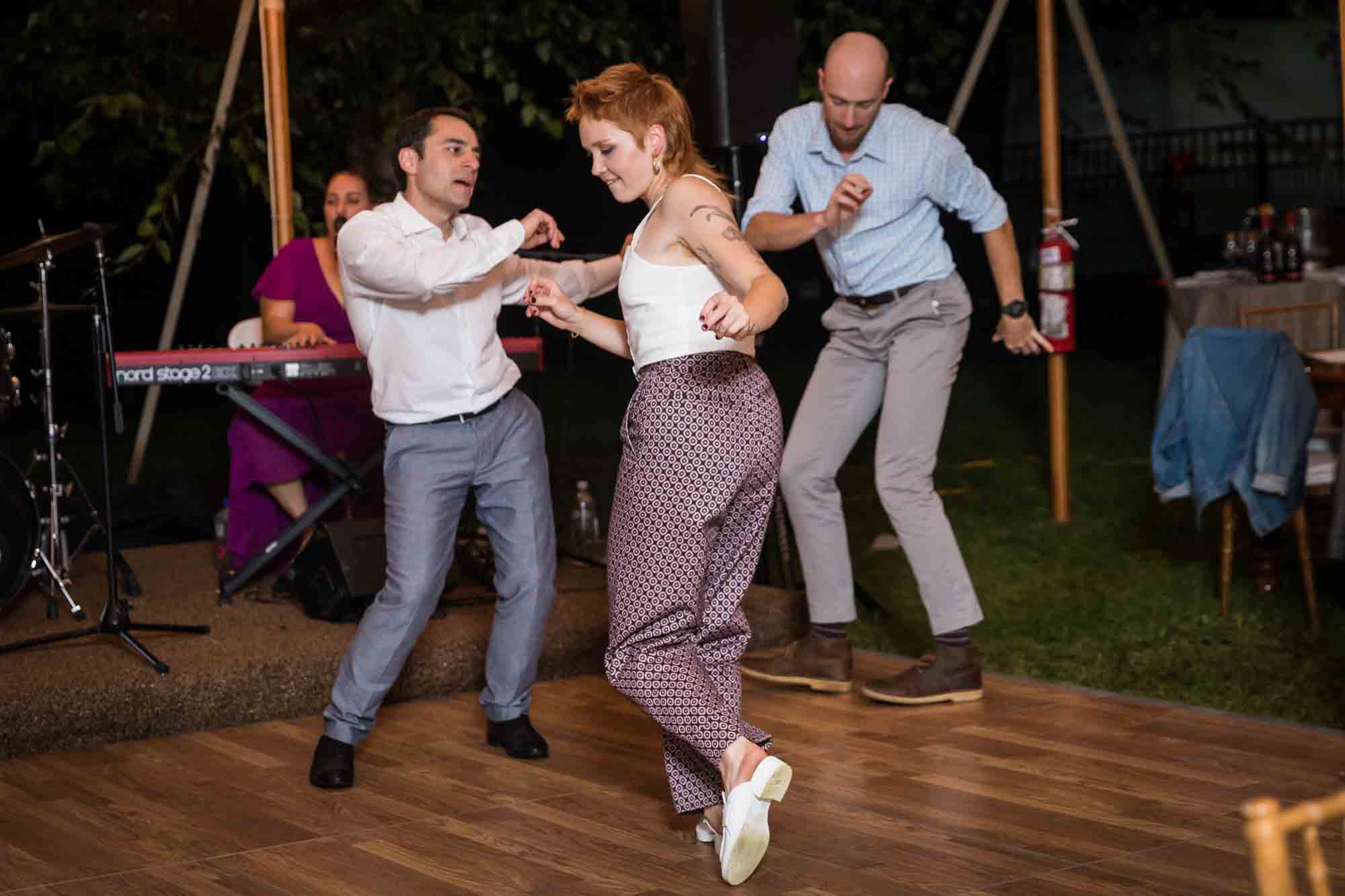 Two men and one woman dancing on dance floor