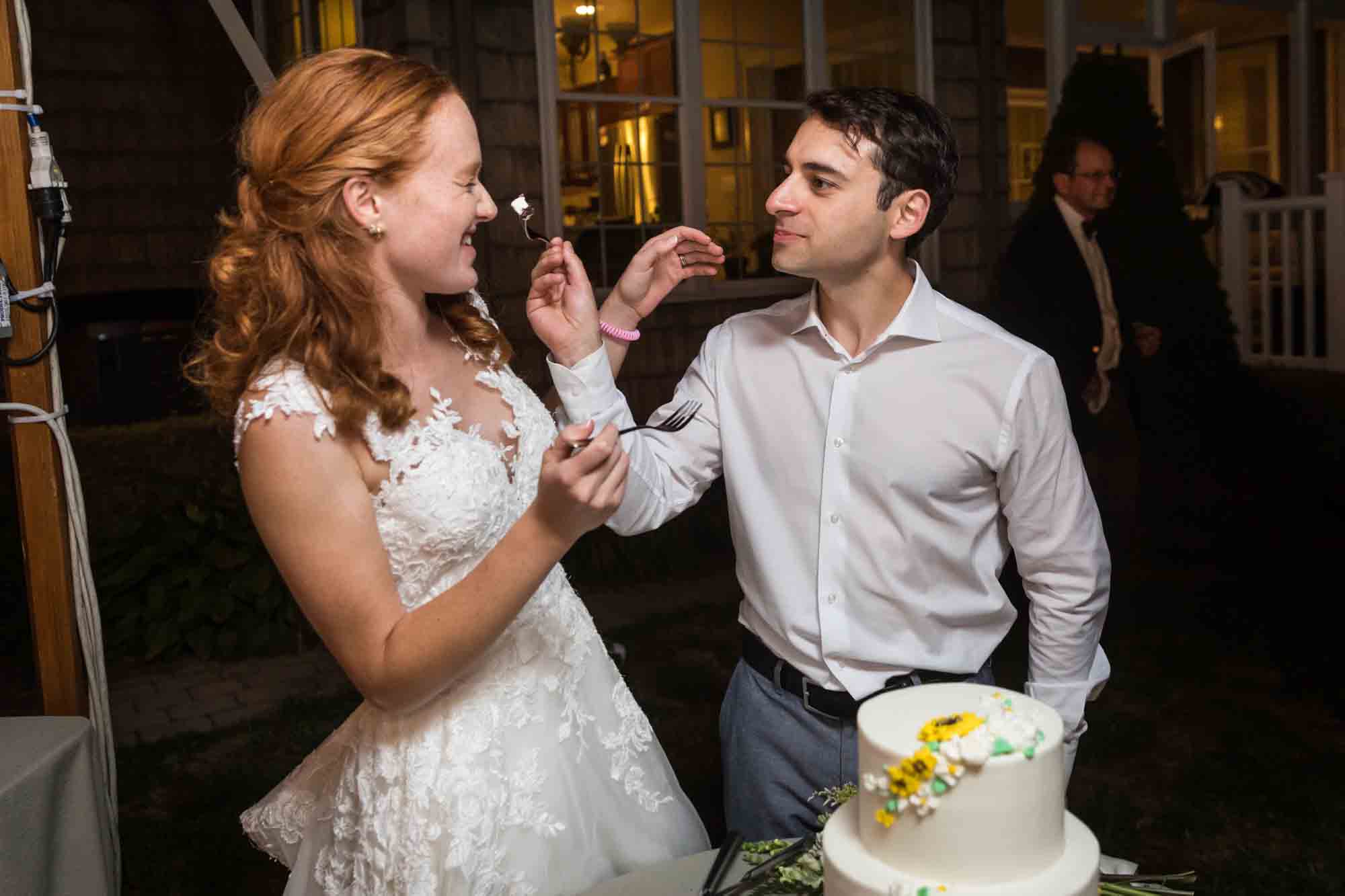 Bride and groom playing during cake cutting for an article on backyard wedding tips
