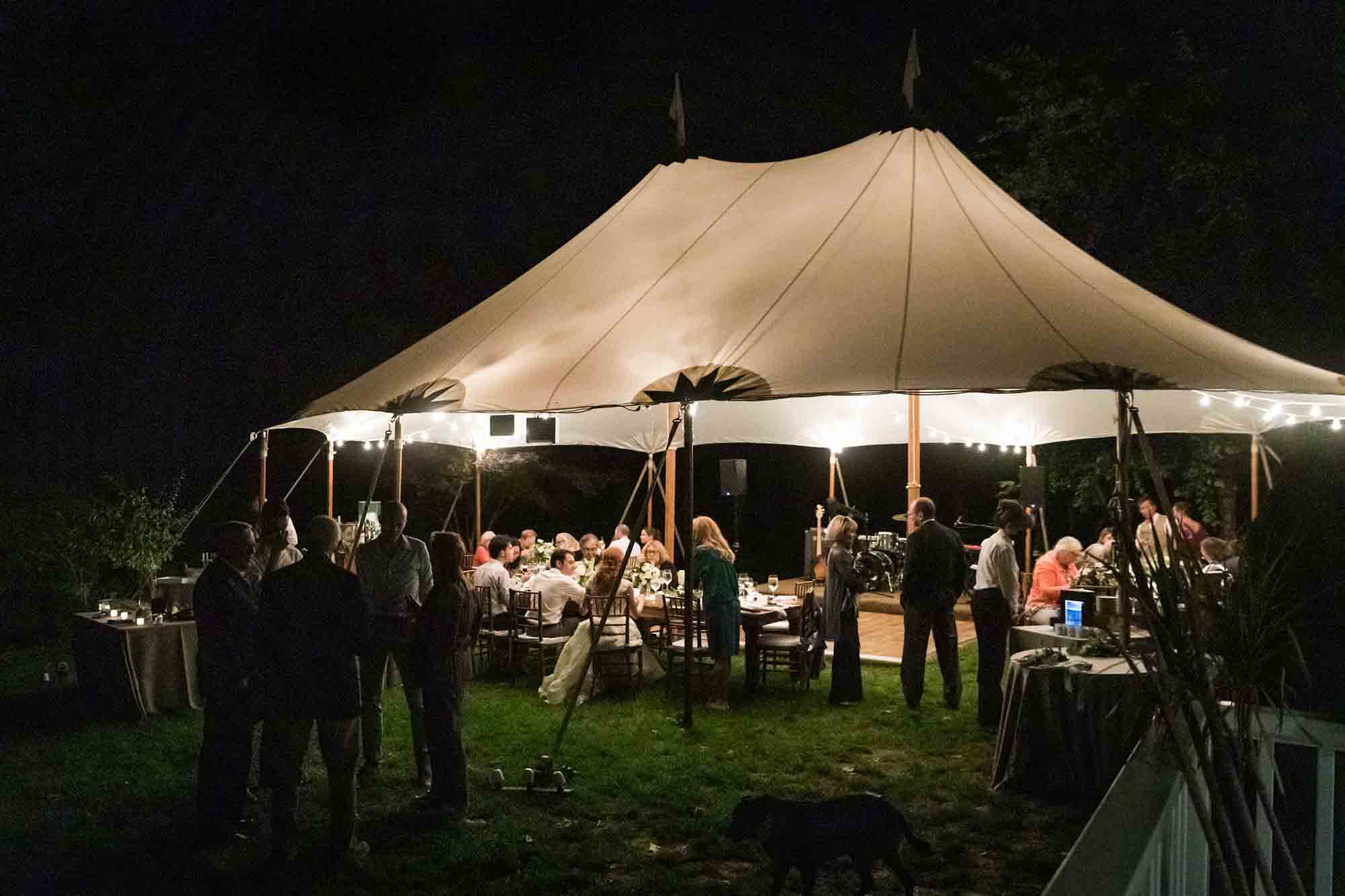 White tent at night with guests for an article on backyard wedding tips
