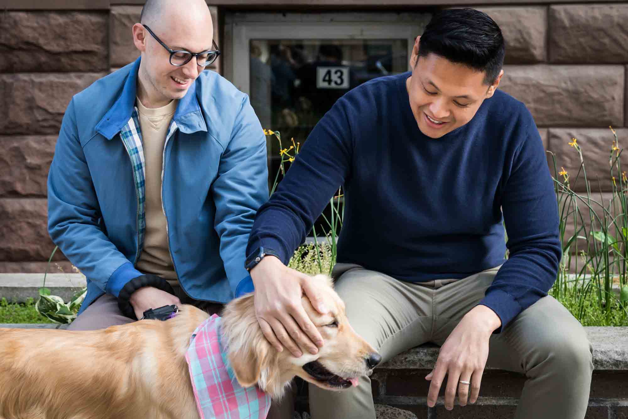 Two men petting a golden retriever wearing a scarf 