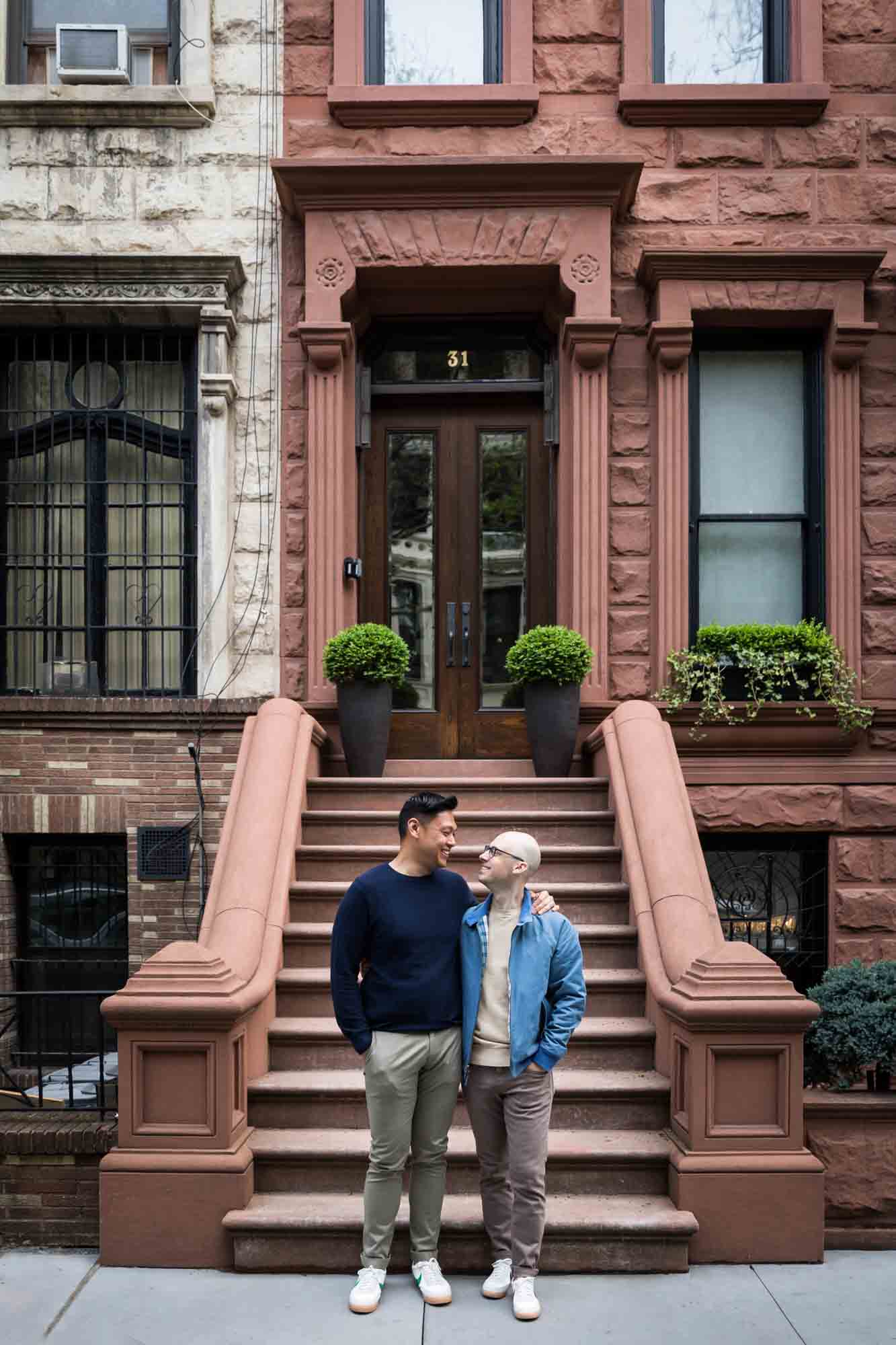 Two men hugging in front of brownstone steps