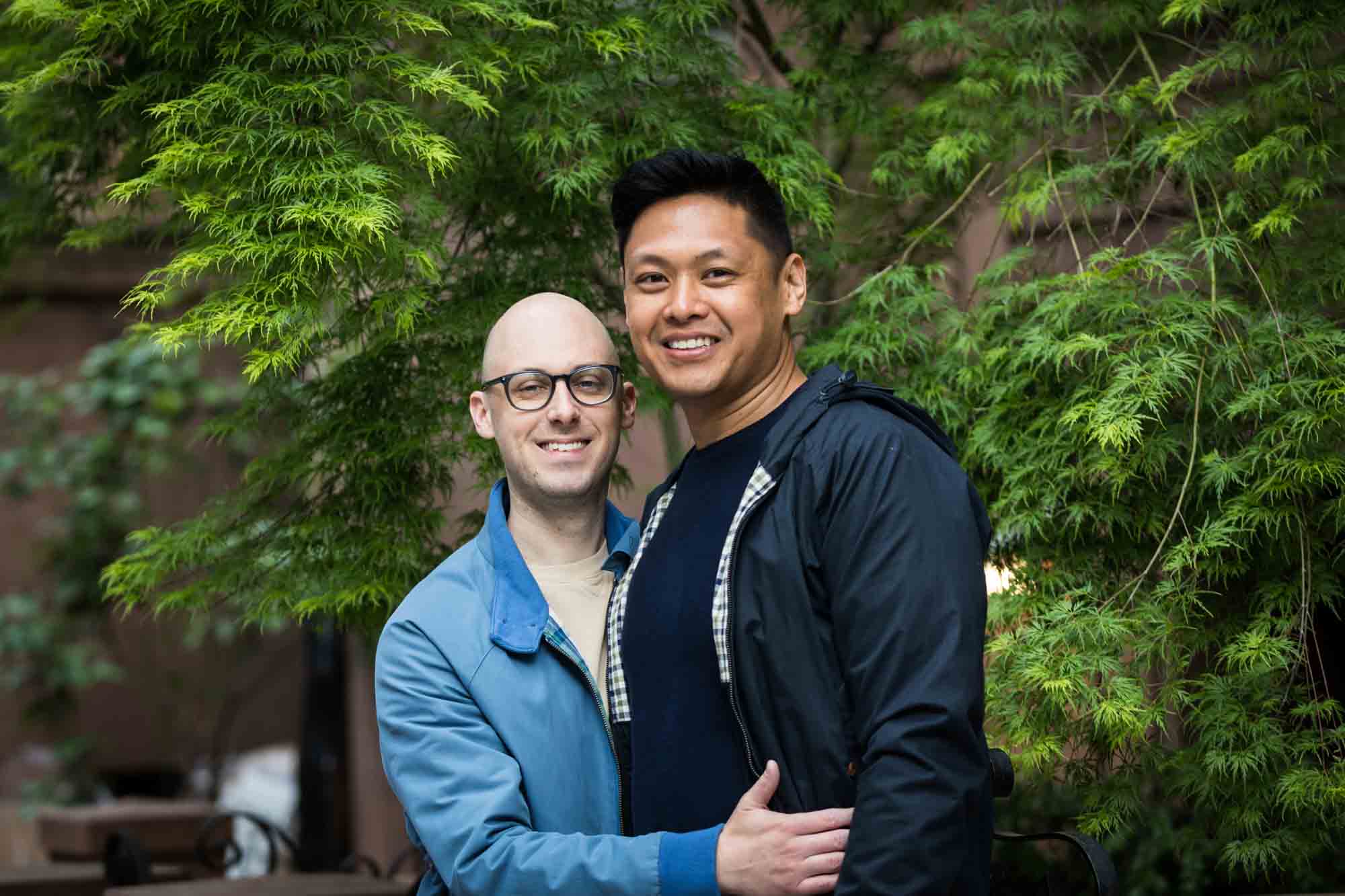 Two men hugging with tree in background