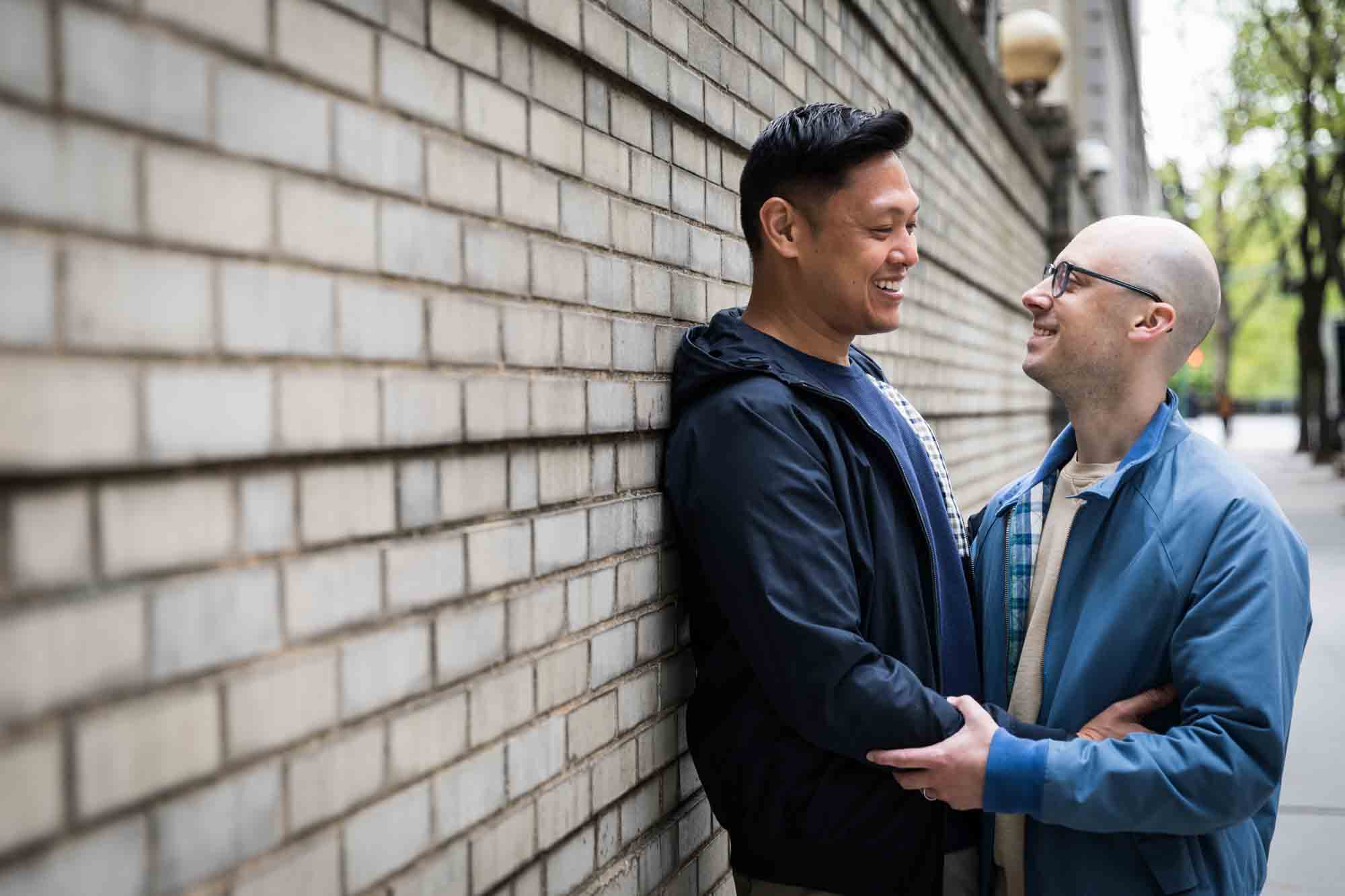 Two men embracing in front of brick wall