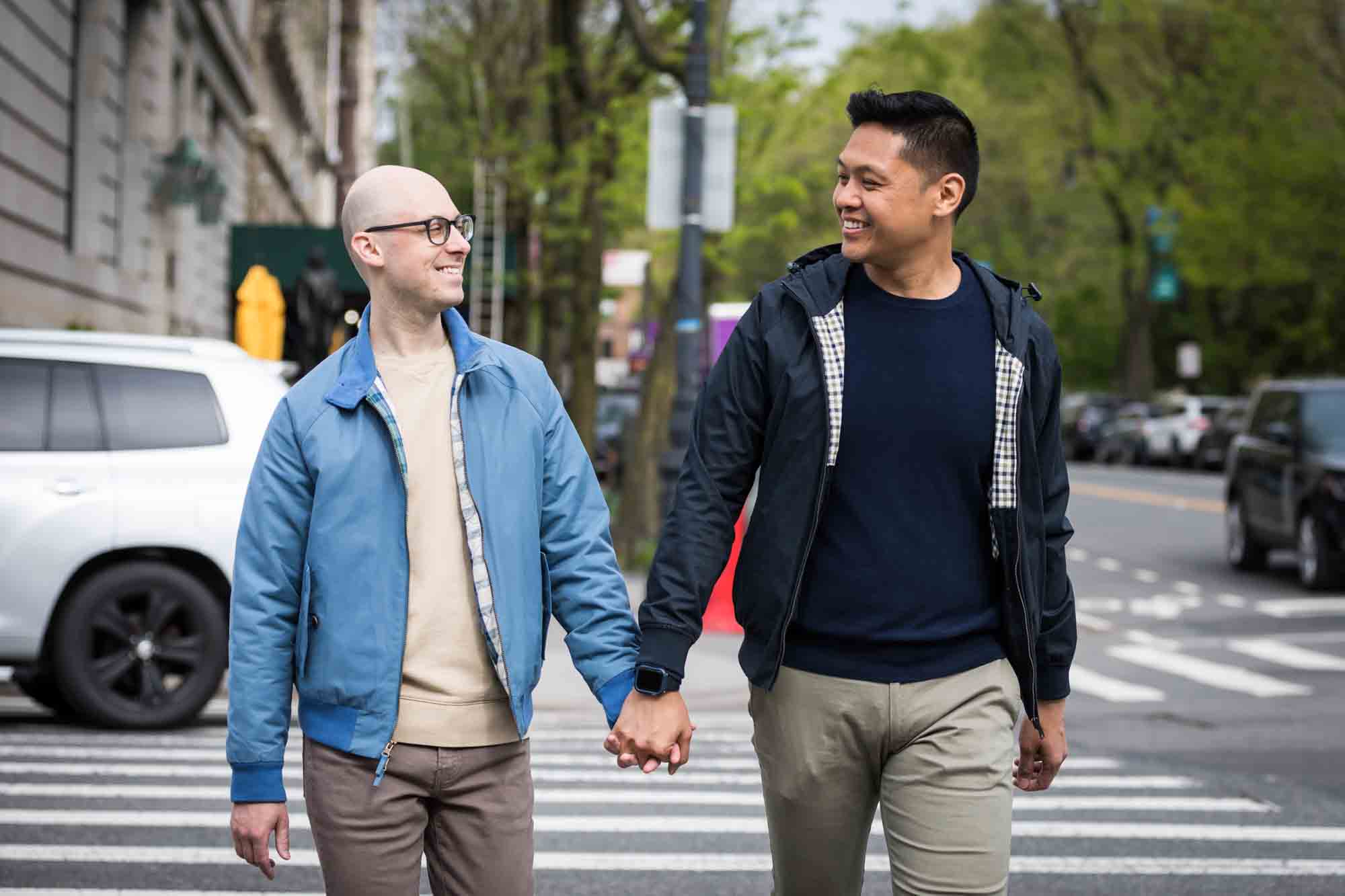 Two men holding hands and walking in NYC crosswalk