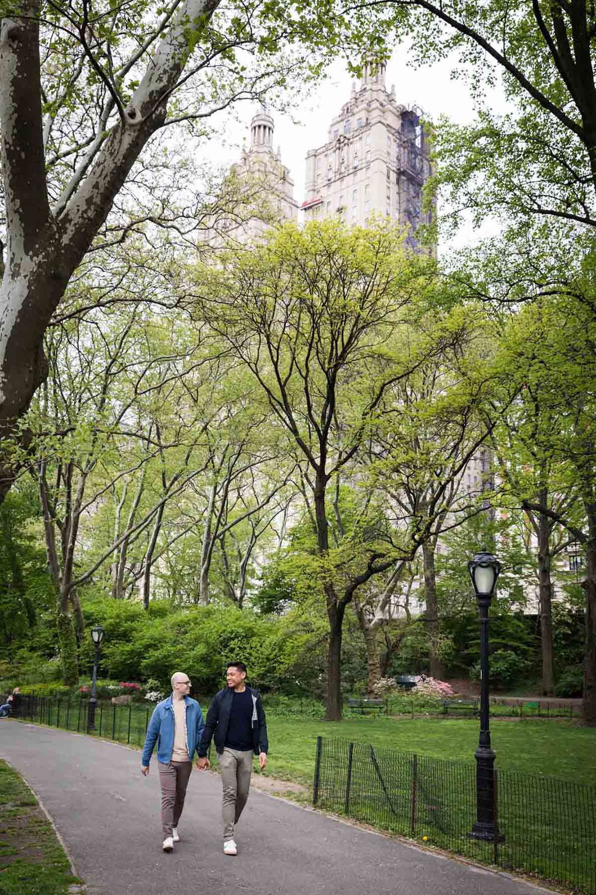 Two men walking along pathway from a Central Park engagement photo shoot