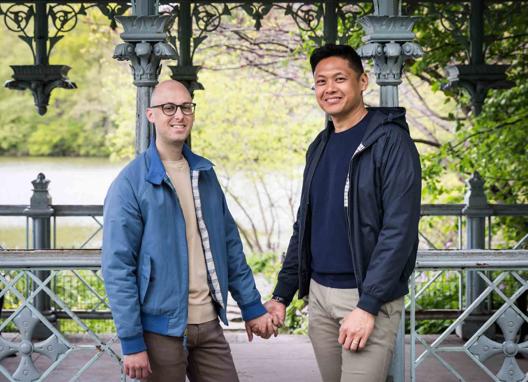 Two men holding hands in front of Ladies Pavilion porch in Central Park