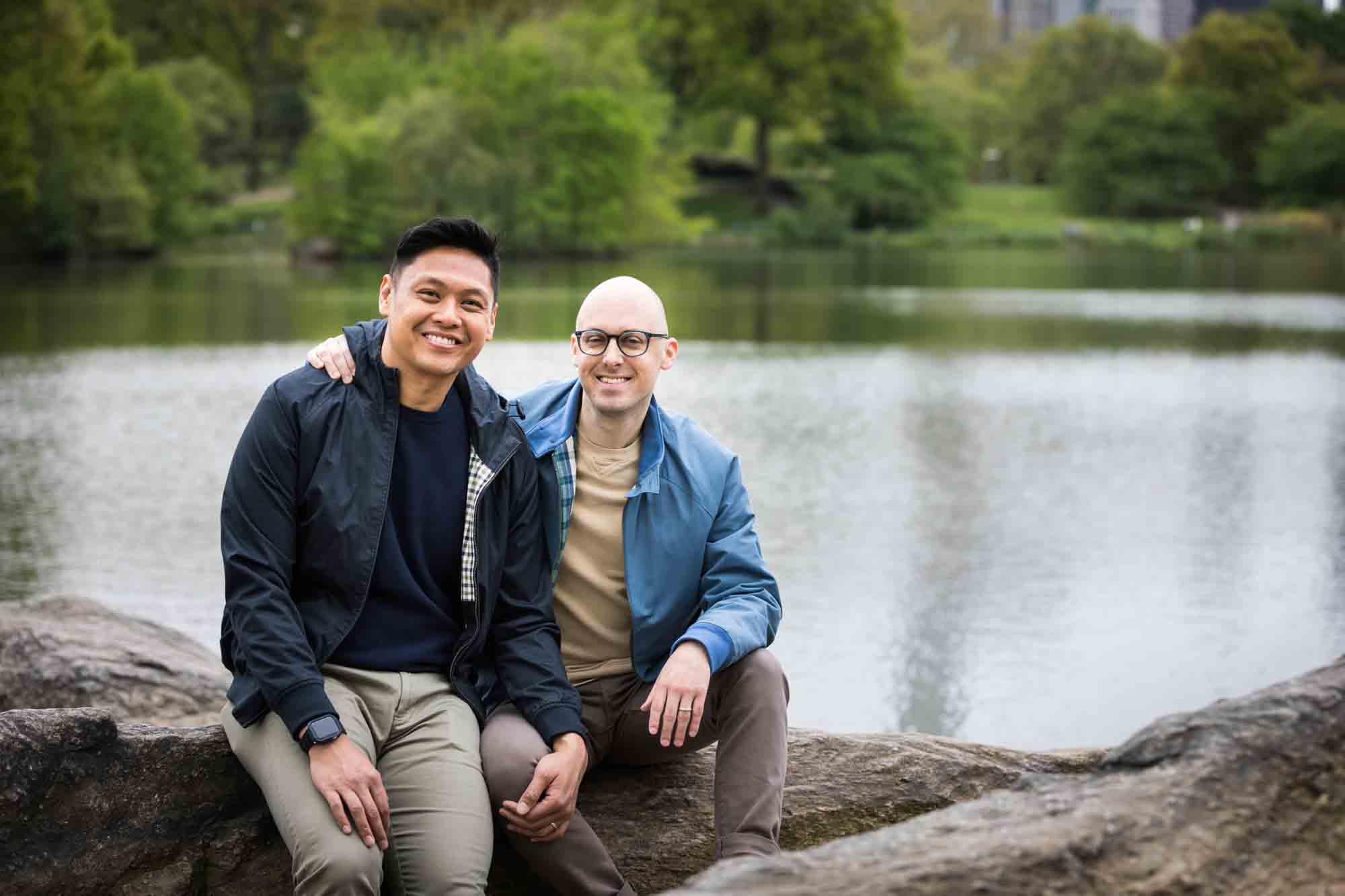 Two men sitting on rock in front of Central Park Lake