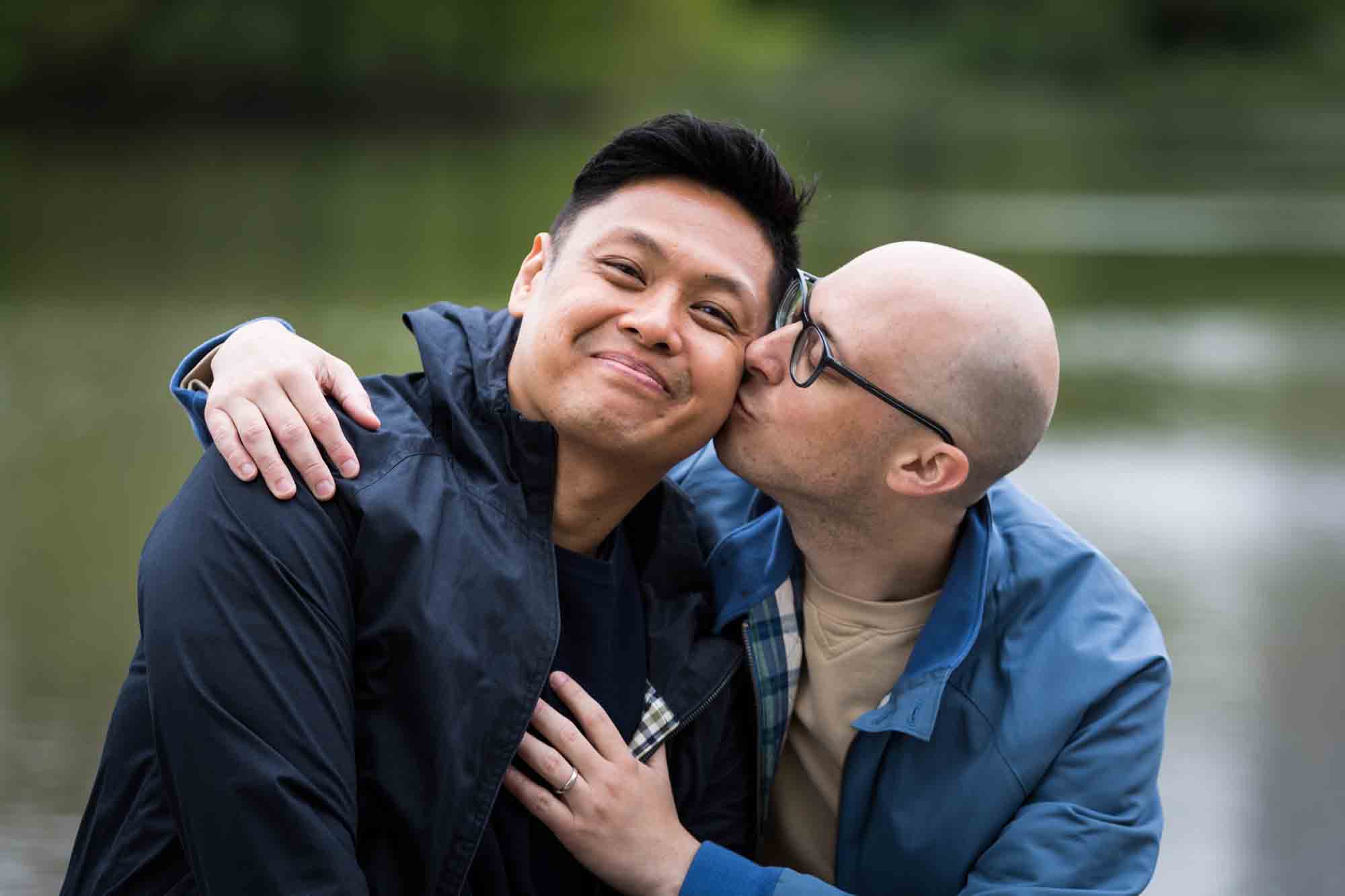 Man kissing another man on the cheek in Central Park