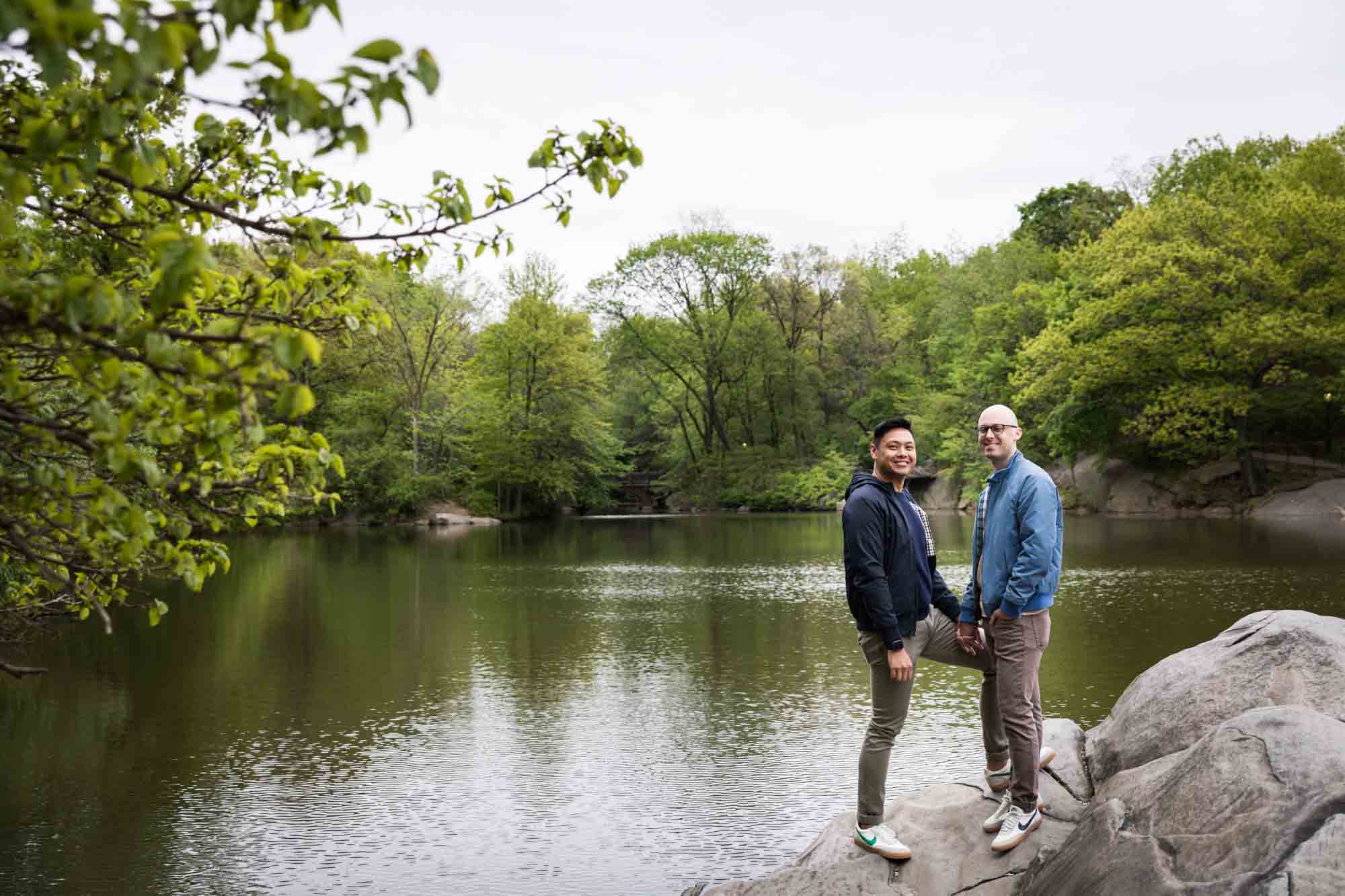 Two men standing on rock in front of Central Park Lake
