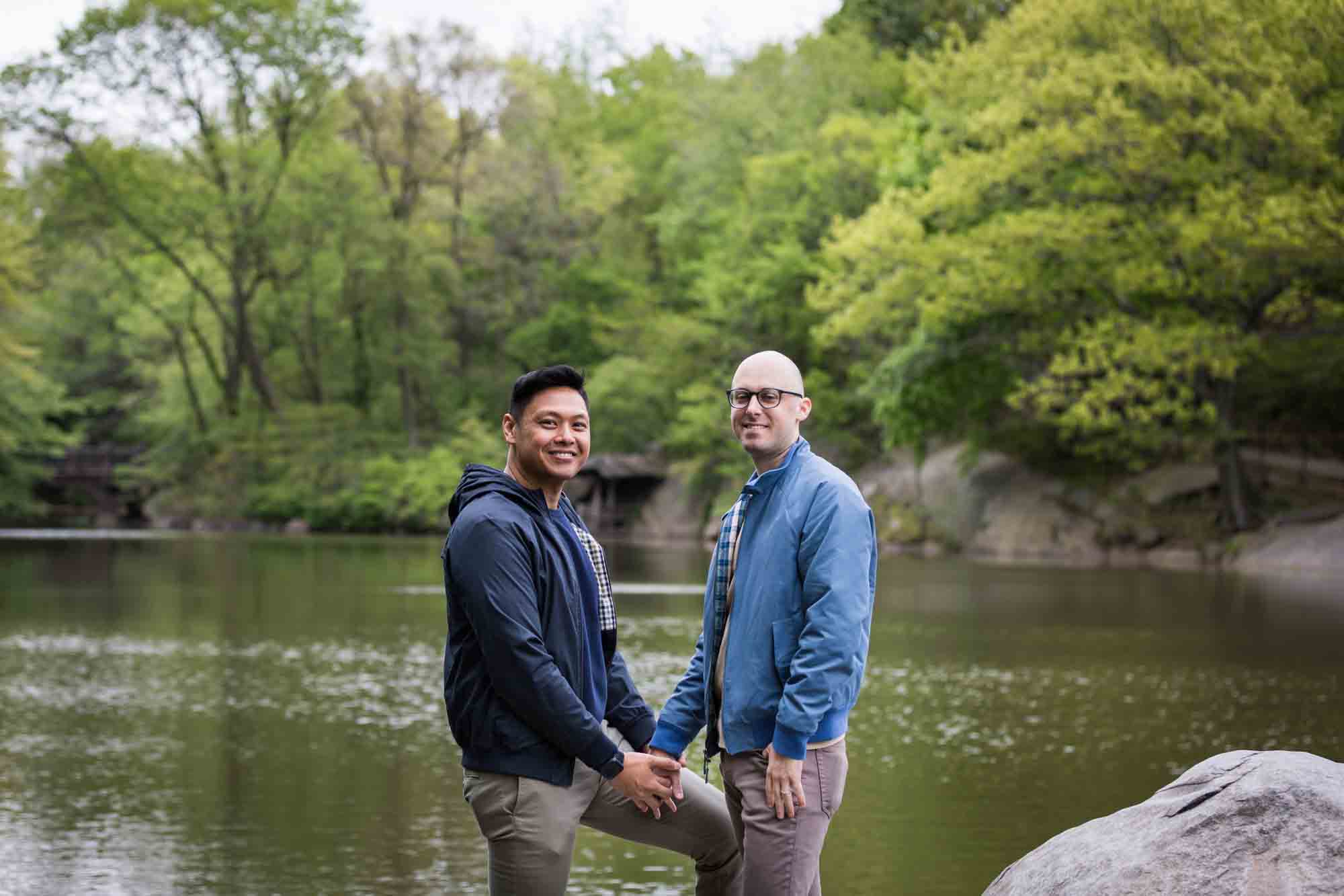 Two men holding hands in front of Central Park Lake