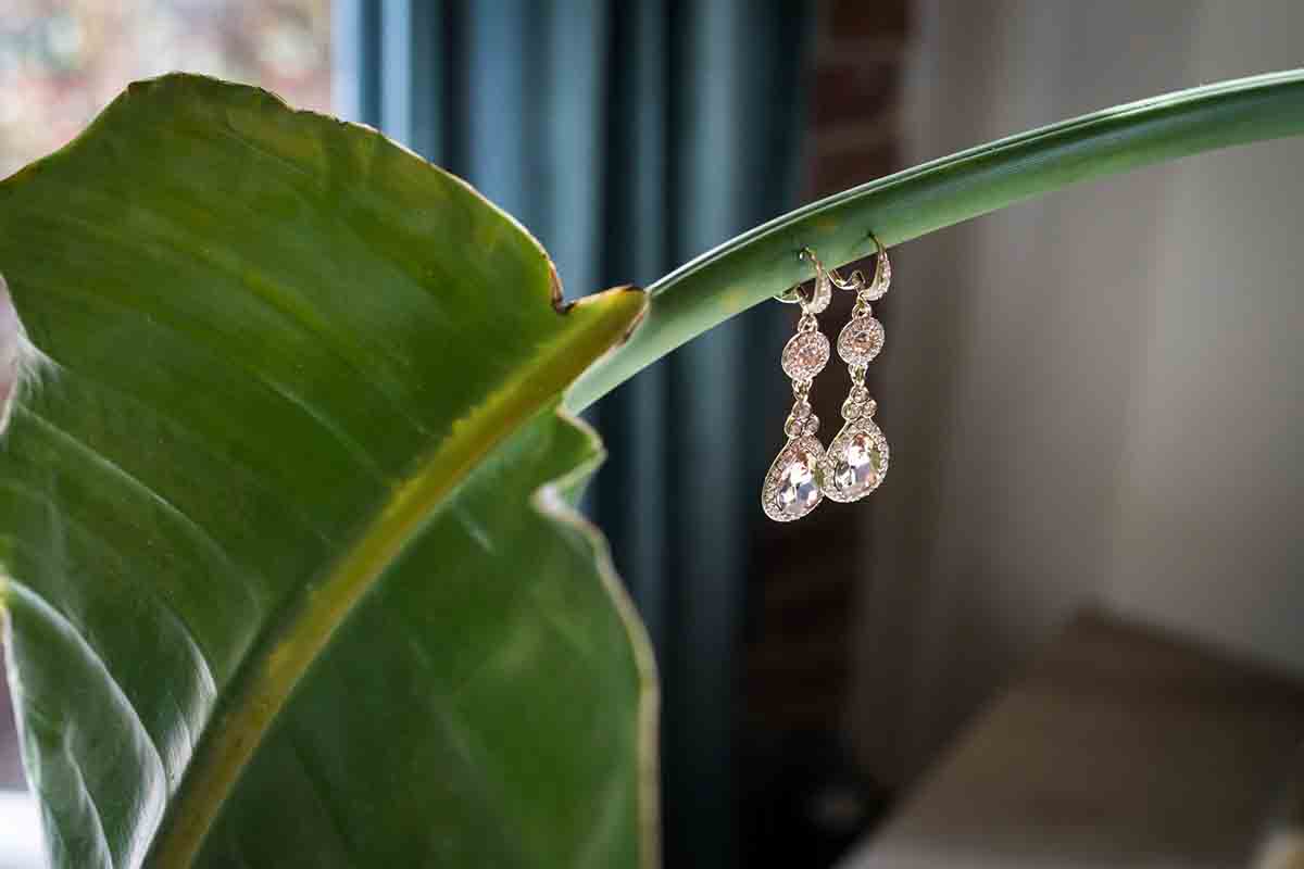 Pair of diamond dangling earrings hanging from leaf stem