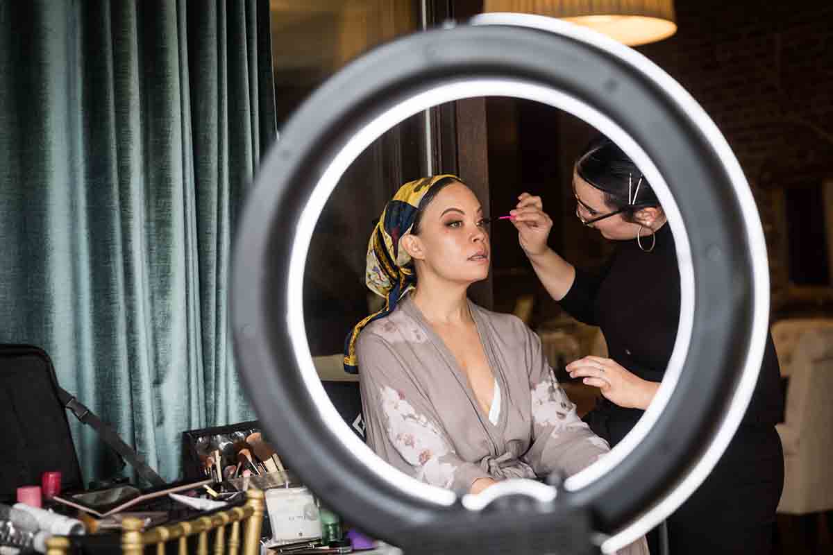 Makeup being applied to bride as viewed through circular light
