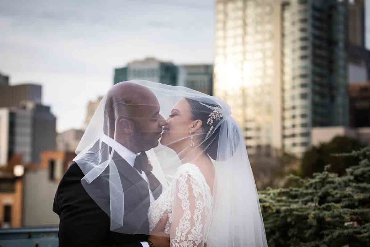Deity wedding photos of bride and groom kissing underneath veil