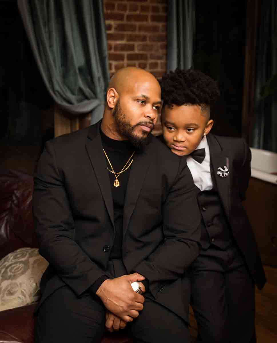 African American man and young boy both wearing black suits