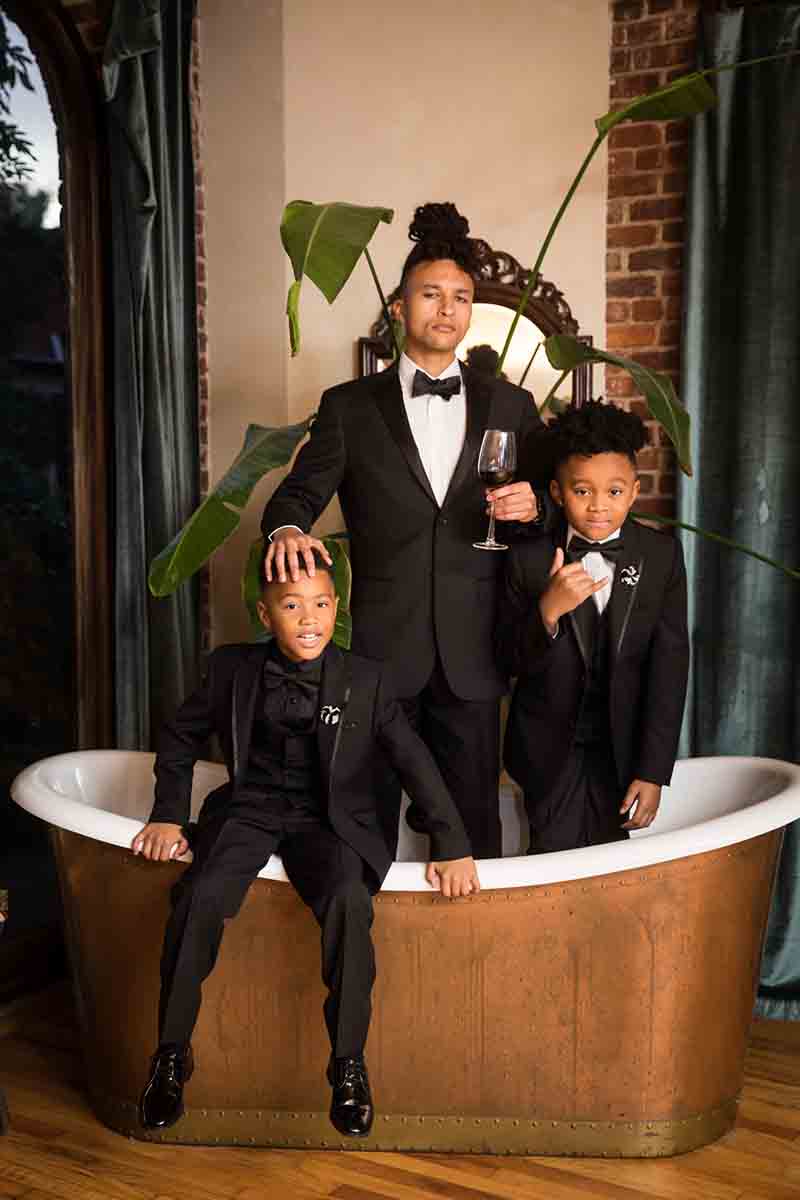 Three young boys standing in a copper bathtub