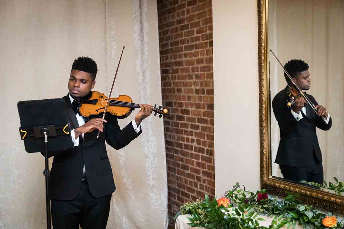 Young African American man playing violin reflected in mirror