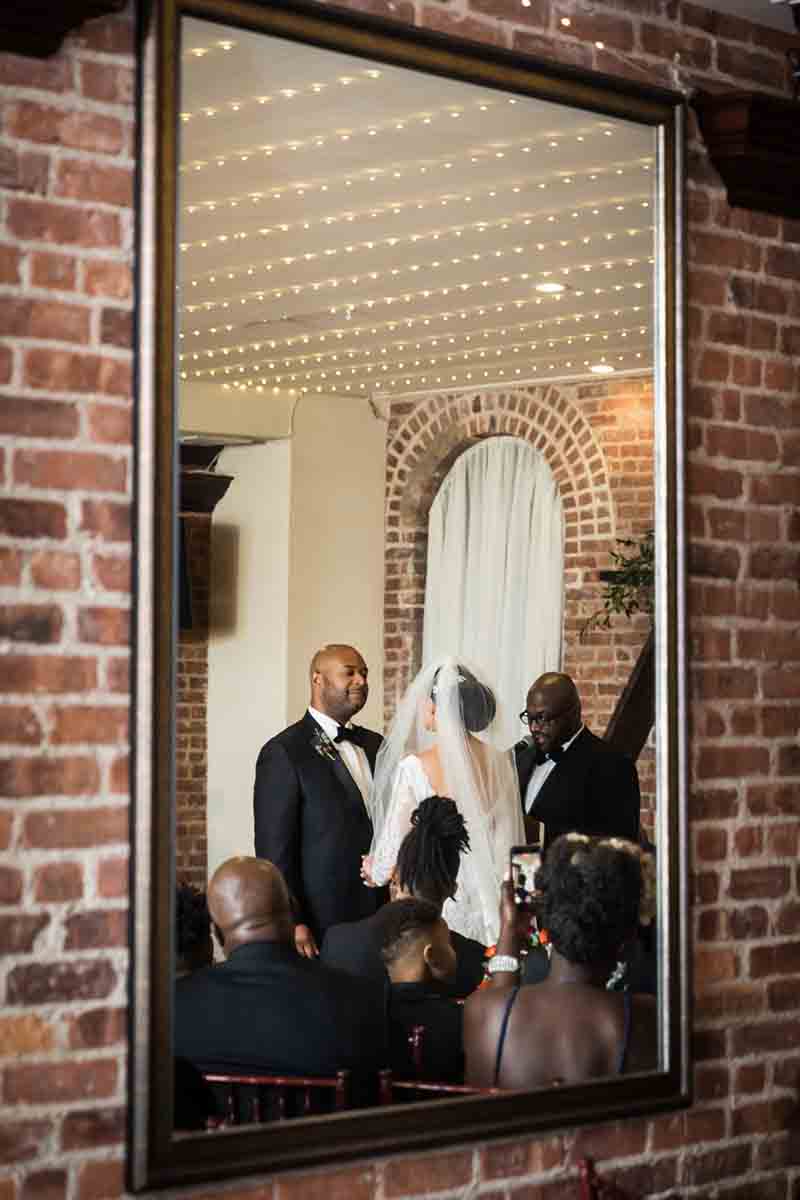 Bride and groom reflected in mirror during ceremony at a Deity wedding
