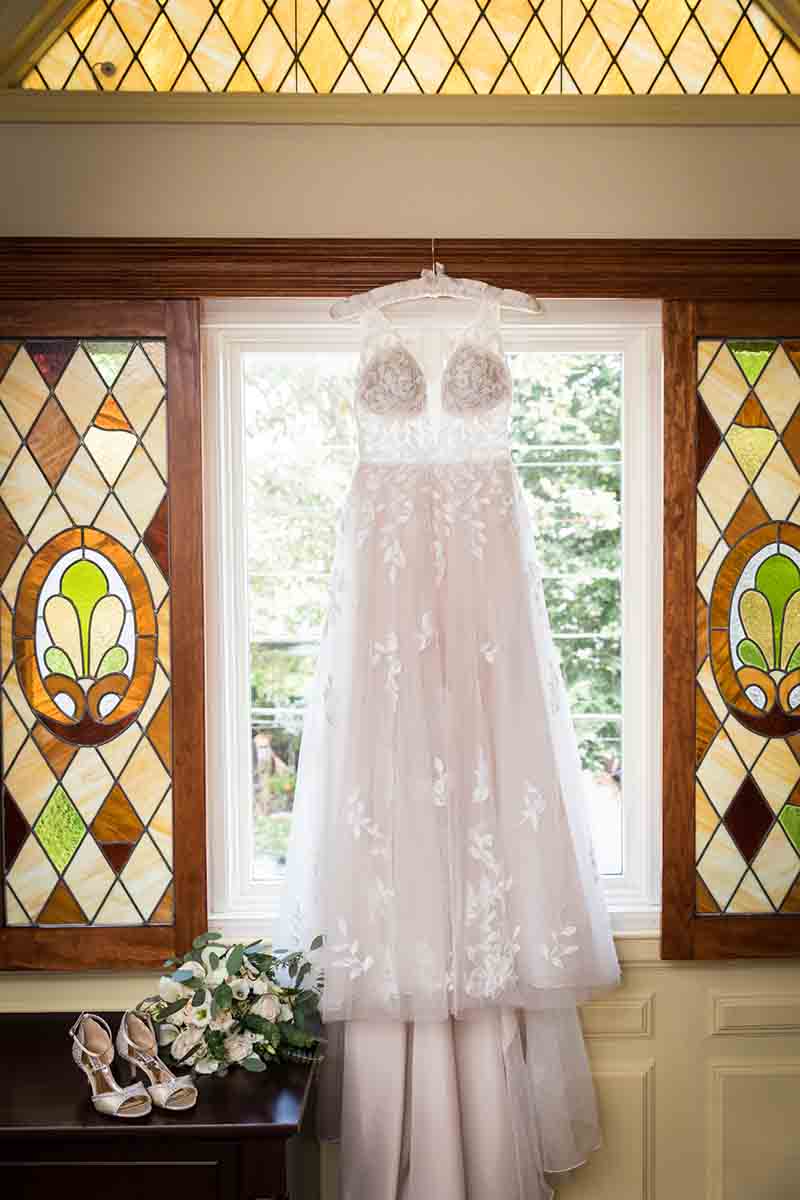 Wedding dress hanging in front of stained glass window