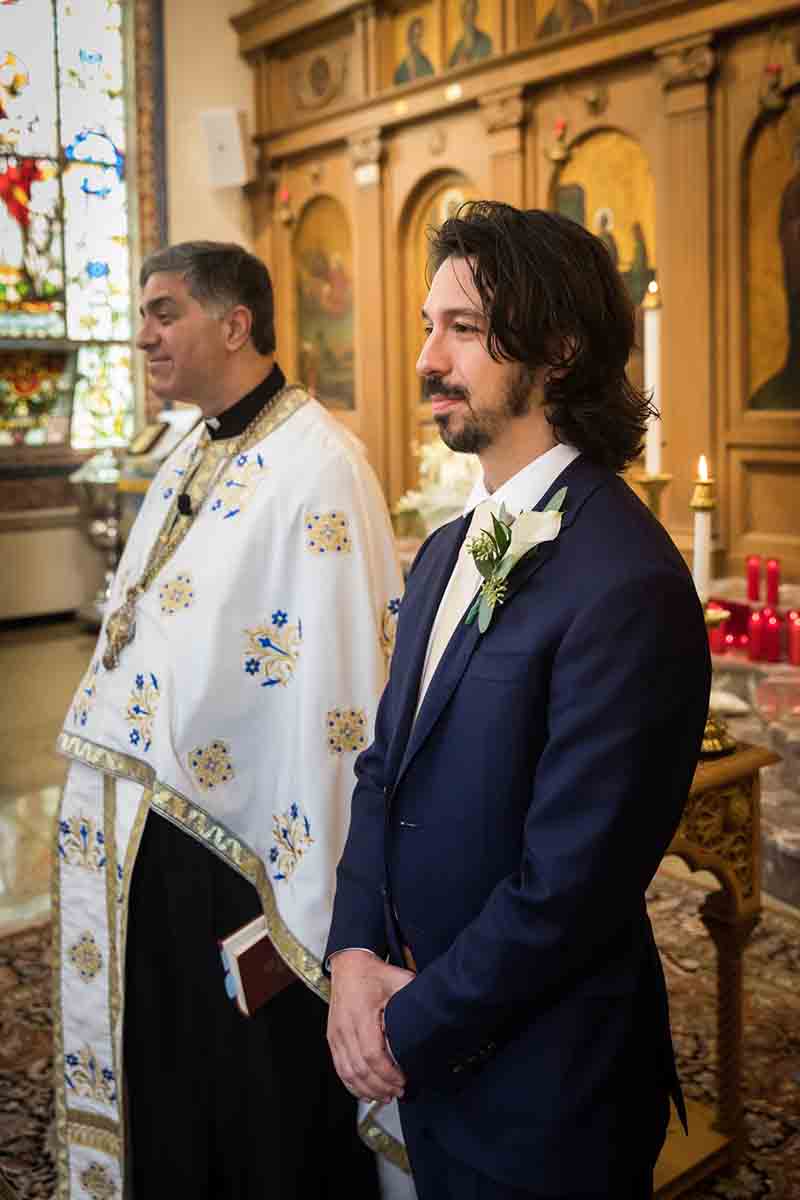 Groom and priest waiting for bride during eastern orthodox wedding ceremony