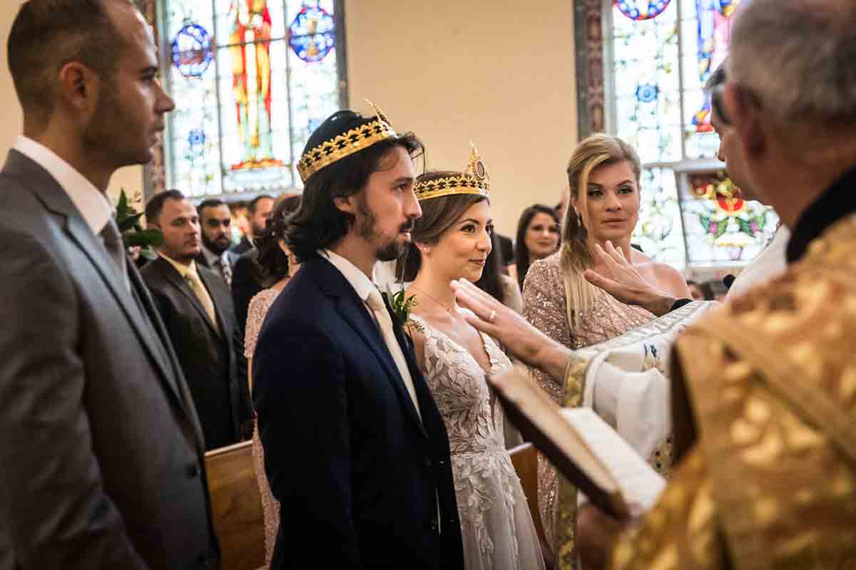 Bride and groom wearing crowns during eastern orthodox wedding ceremony