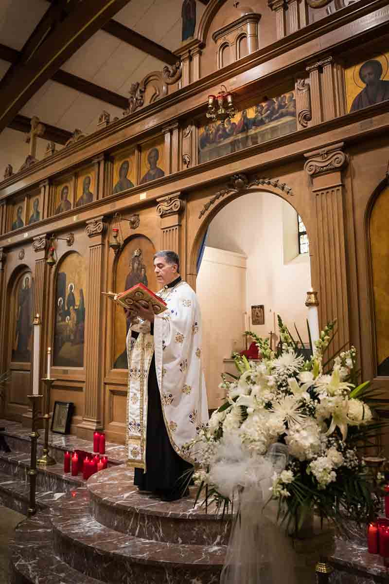 Priest holding the Gospel during eastern orthodox wedding ceremony