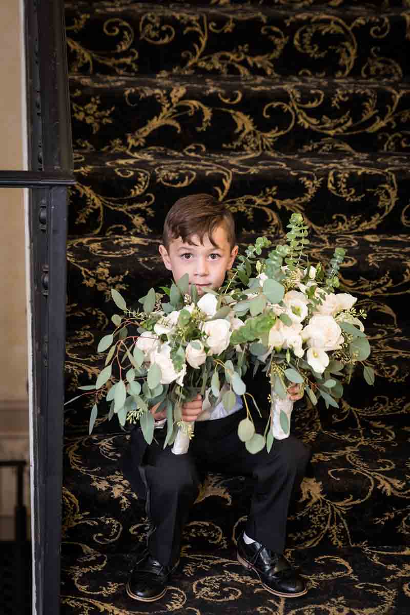 Little boy holding two flower bouquets on the stairs